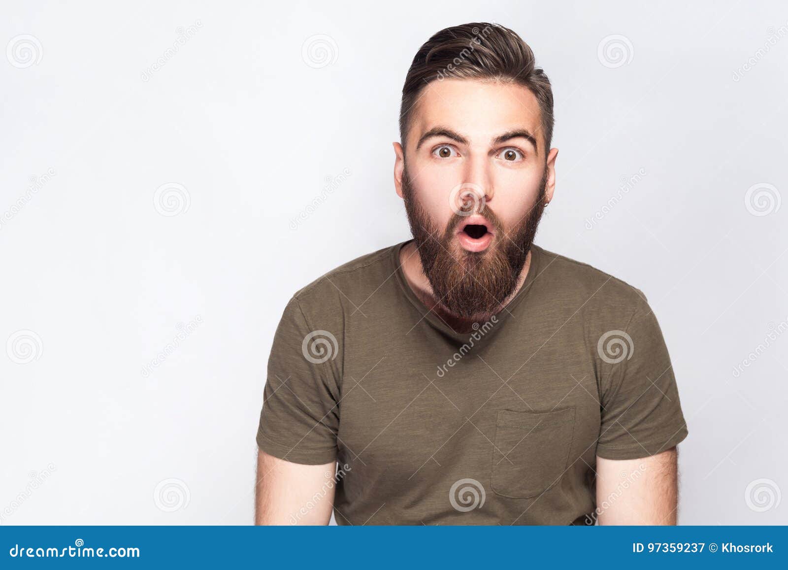 Portrait of Surprised Bearded Man with Dark Green T Shirt Against Light