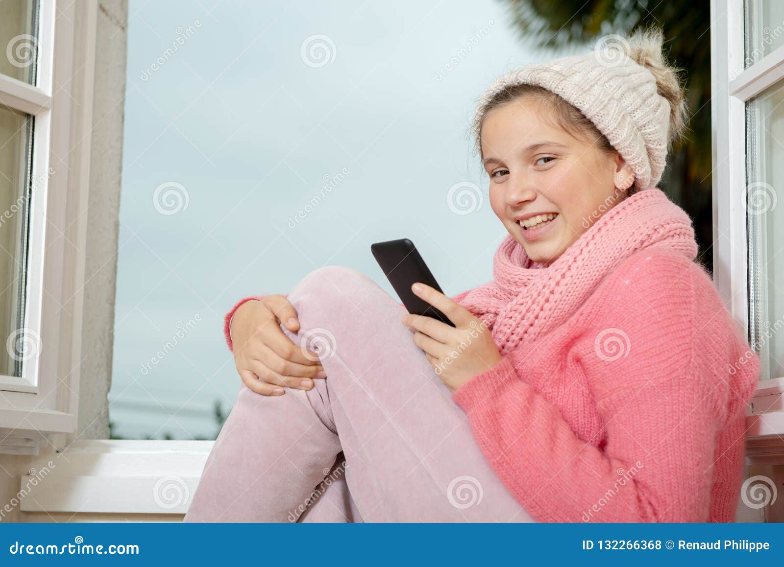 Portrait of Teenage Girl with Pink Sweater Near the Window Using Stock ...