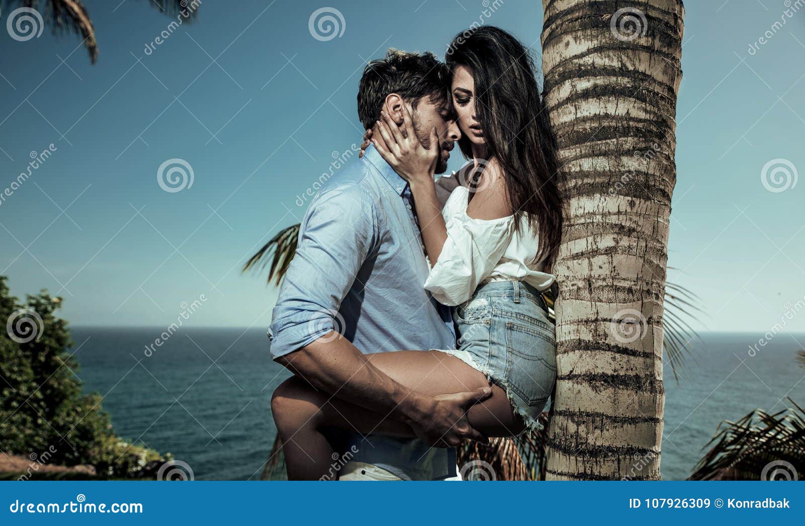 portrait of attractive lovers leaning on a palm tree