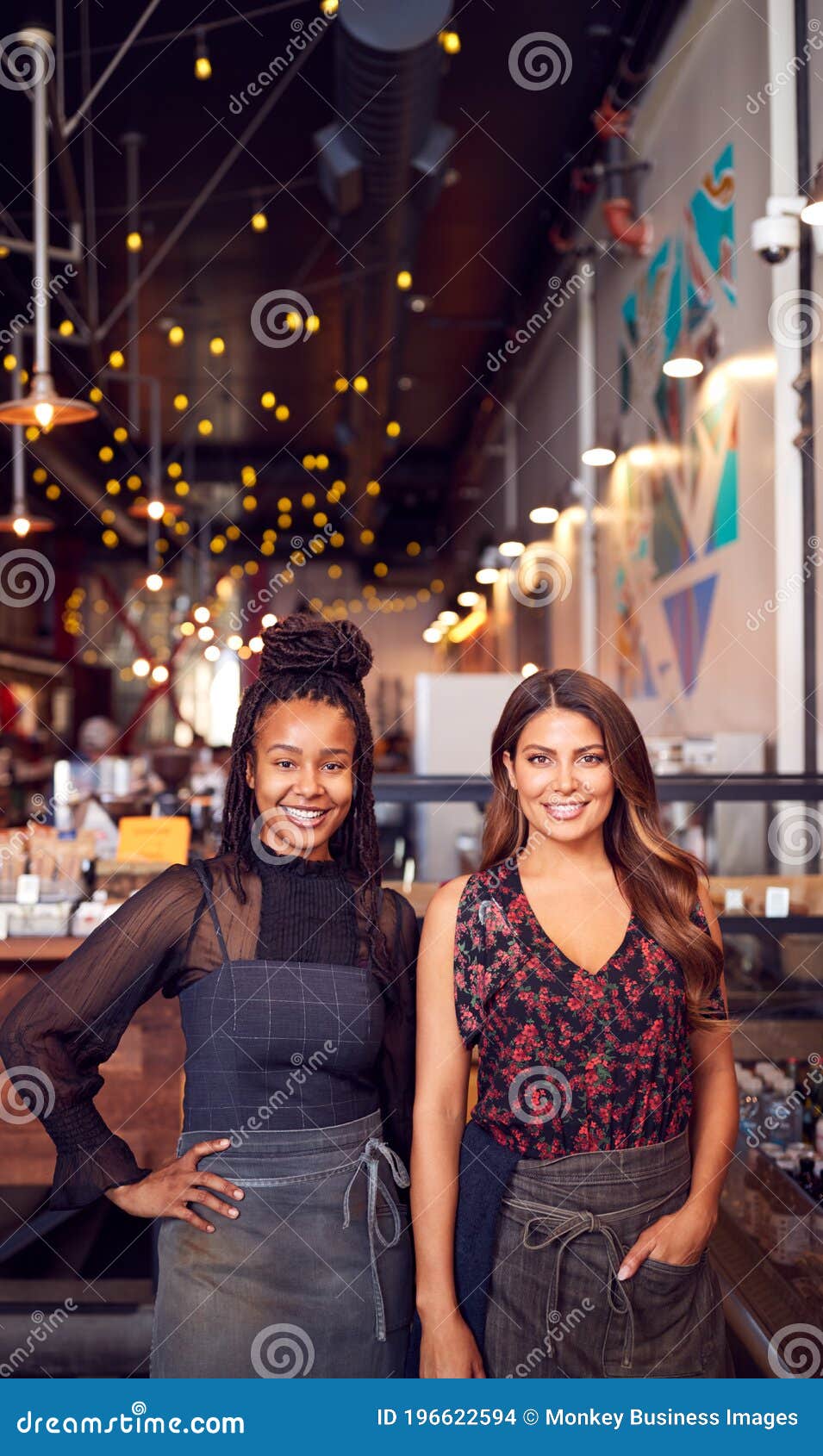 portrait of two female coffee shop owners standing at sales desk