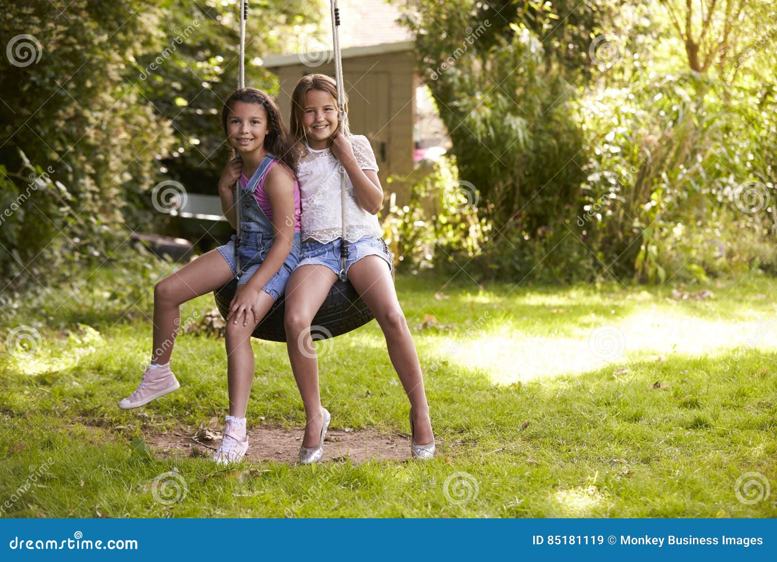 Two Girls Sharing An Tree Swing Stock Photo - Download Image Now