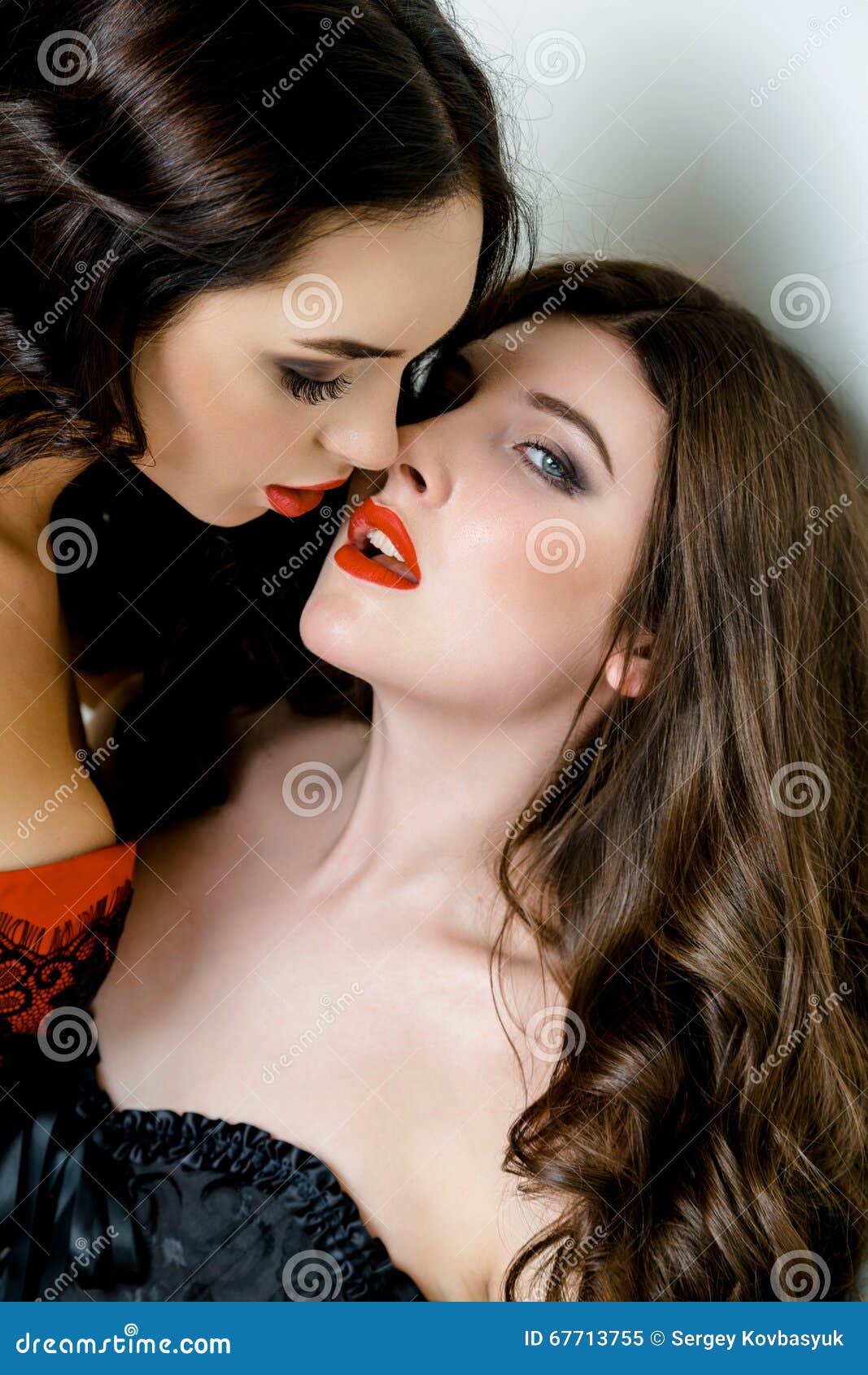 portrait of two gorgeous women with red lips moment before kissing.