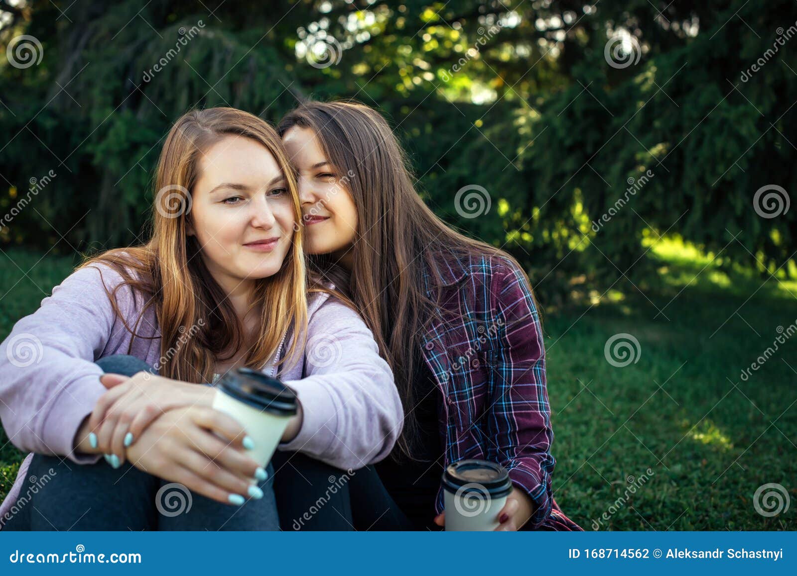 Portrait Of Two Young Beautiful Girls Sitting Next To Each Other On The 