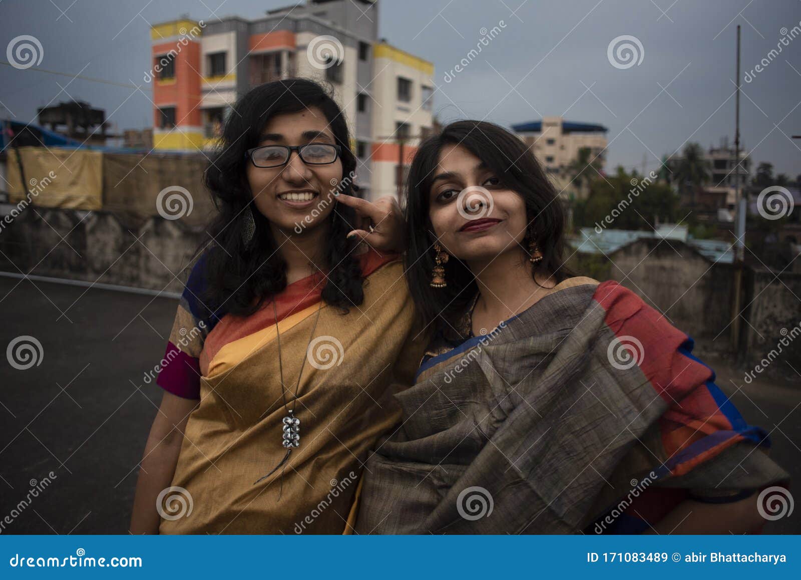 Elegant and fashionable indian friends couple of woman in saree and man in  suit sitting on bench Stock Photo - Alamy