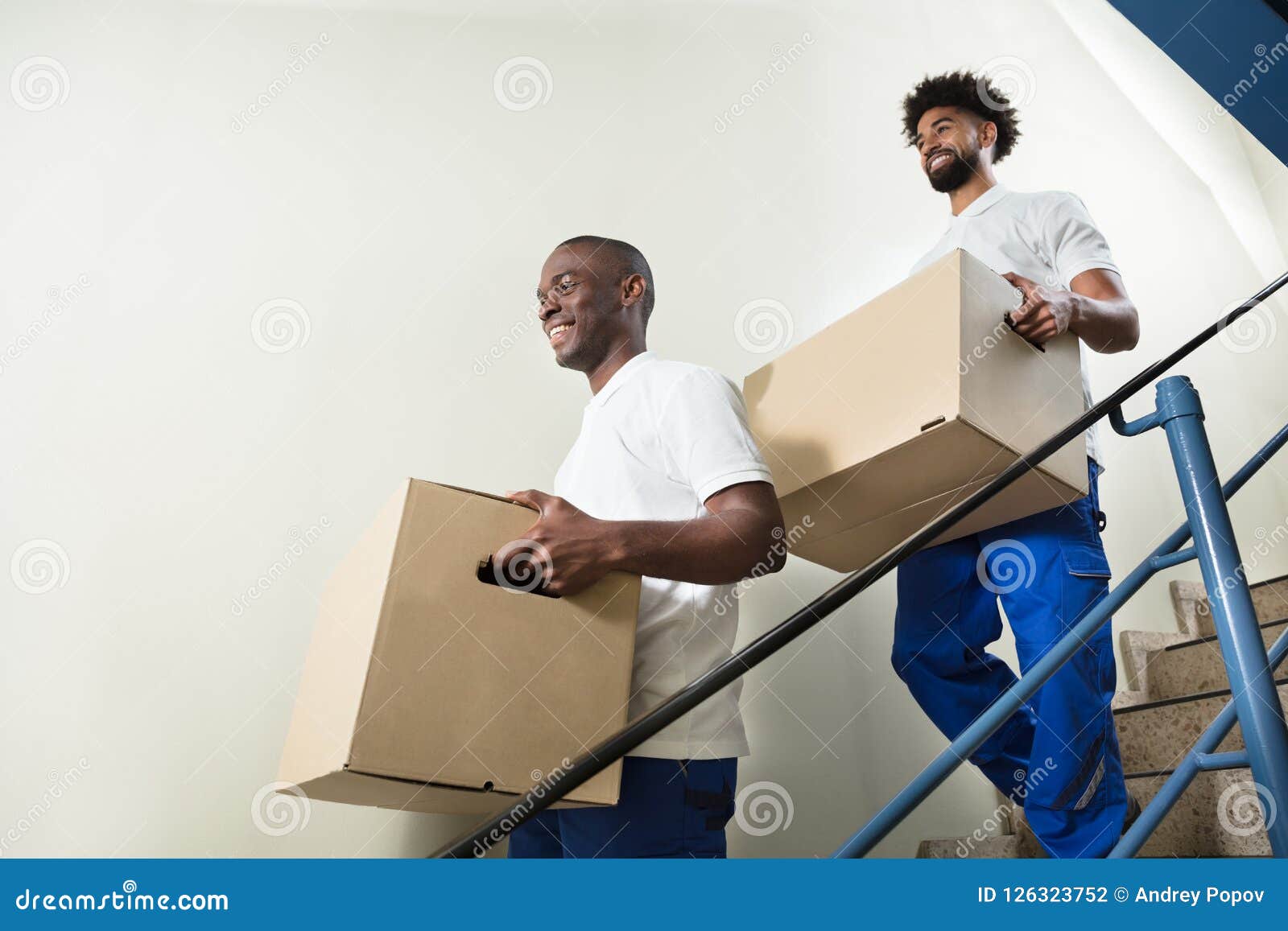 portrait of two movers holding cardboard boxes