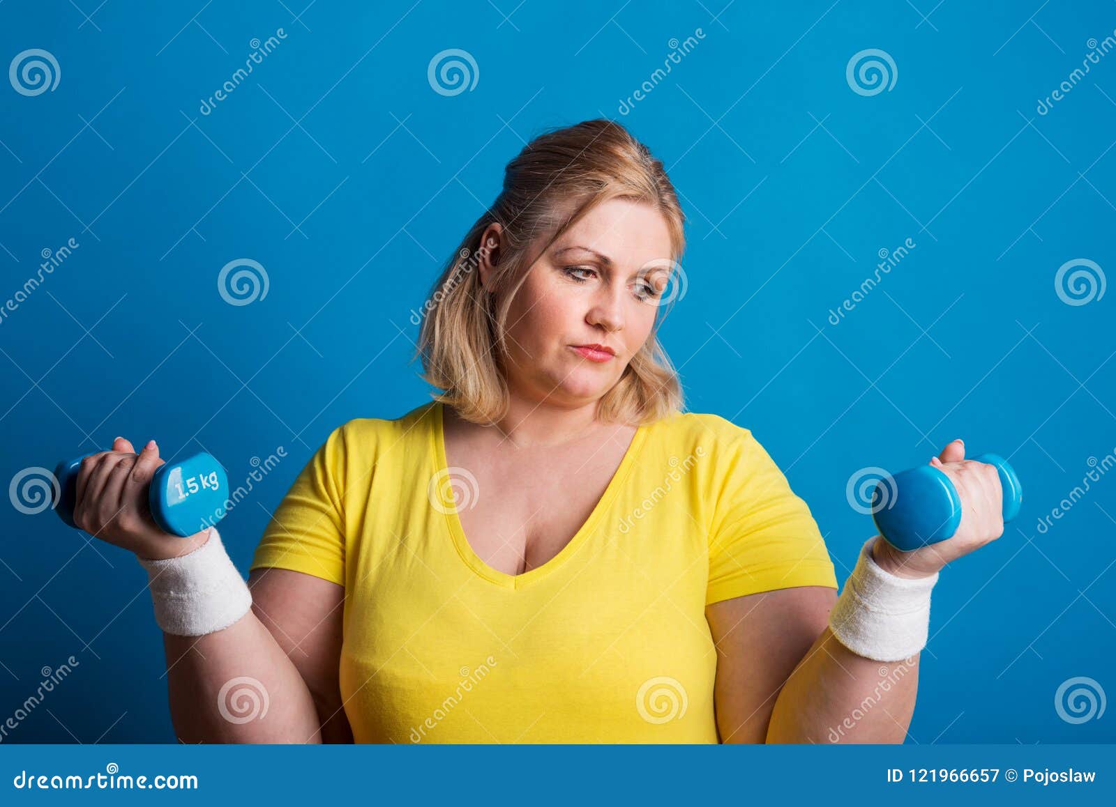 Portrait of an Unhappy Overweight Woman with Dumbbells in Studio on a ...