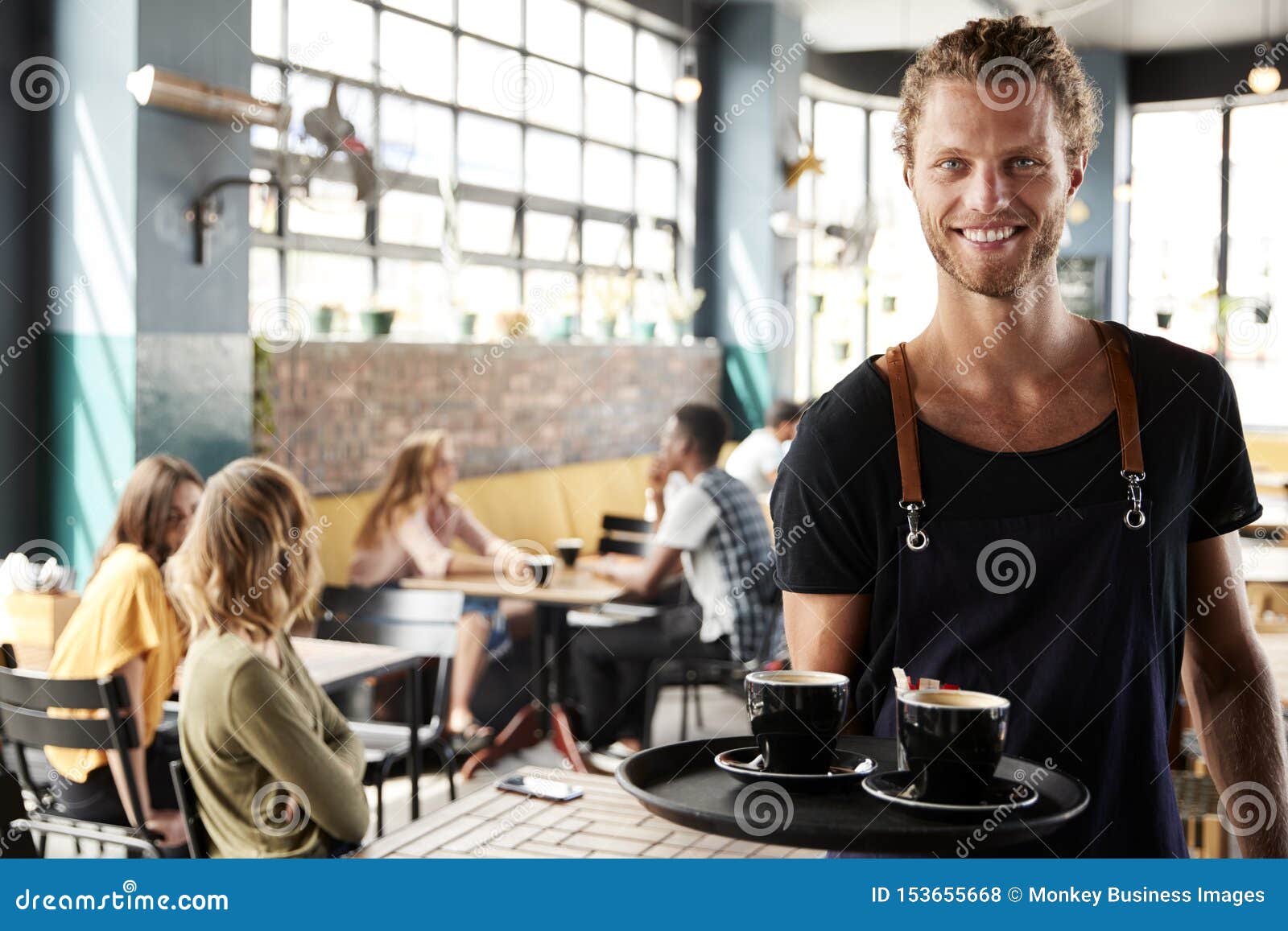 portrait of waiter serving customers in busy coffee shop