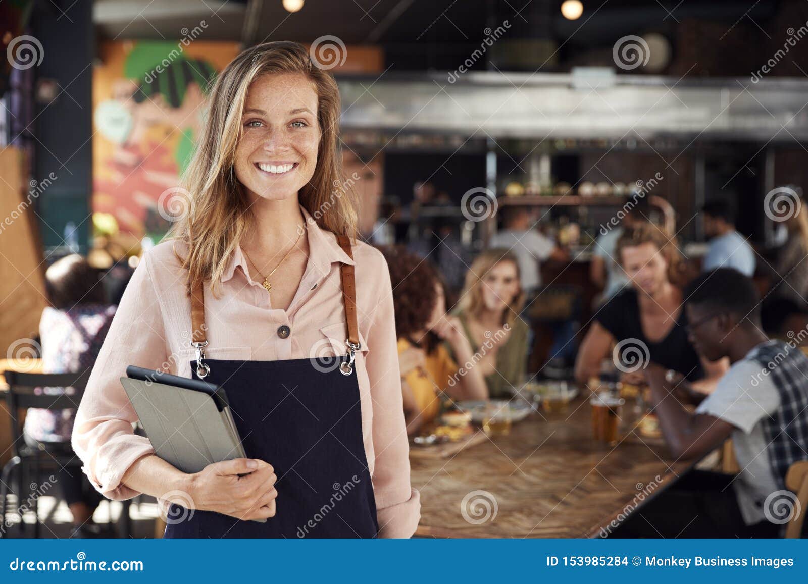 portrait of waitress holding menus serving in busy bar restaurant