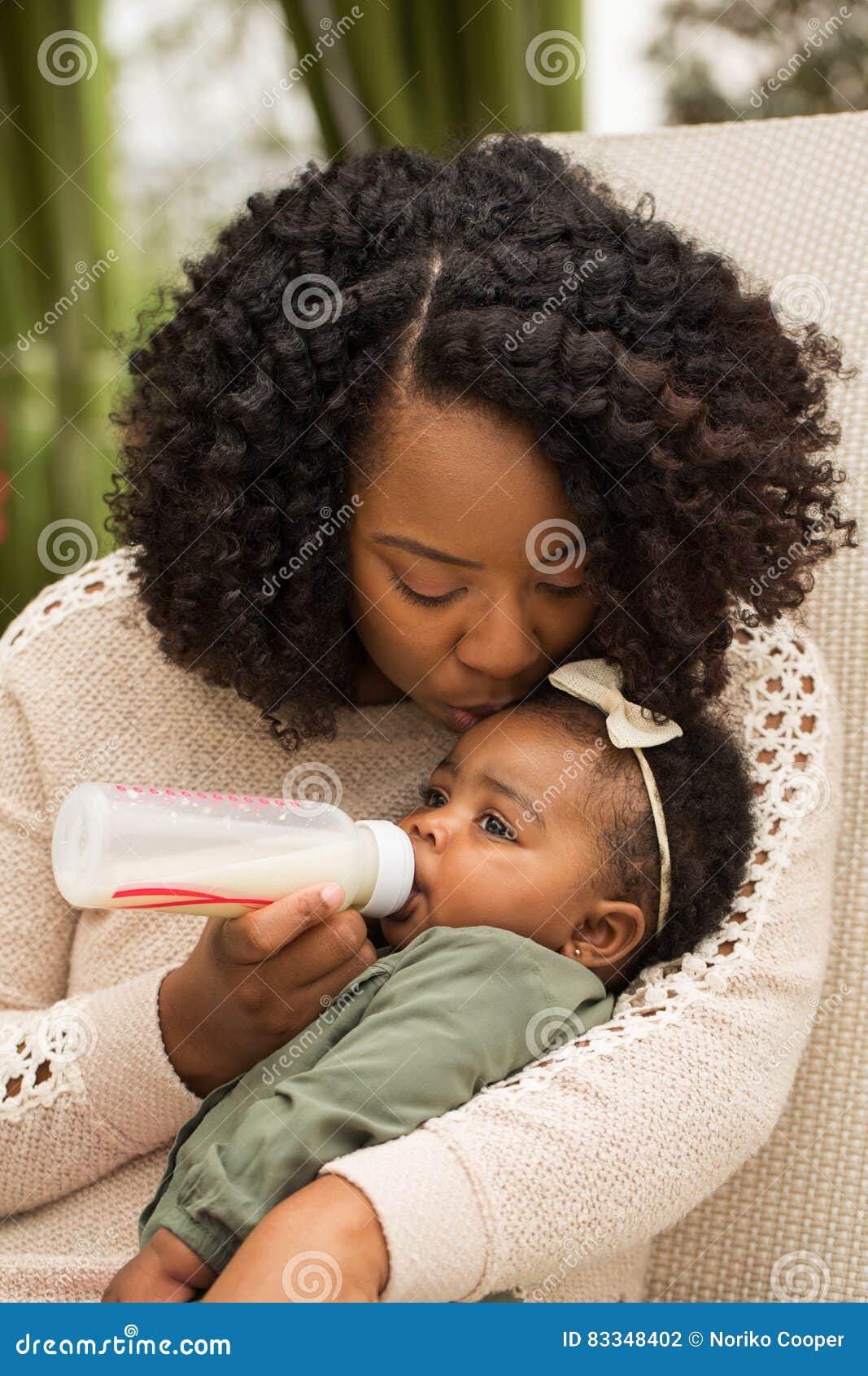 portrait of woman feeding her daughter with a bottle.