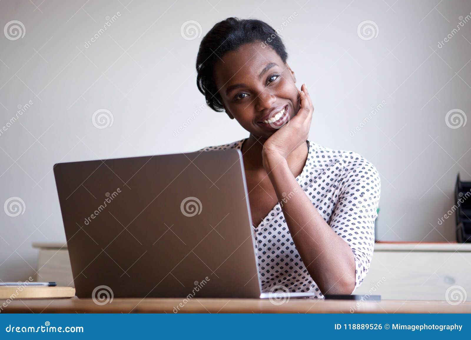 woman resting head on hand sitting at desk with laptop