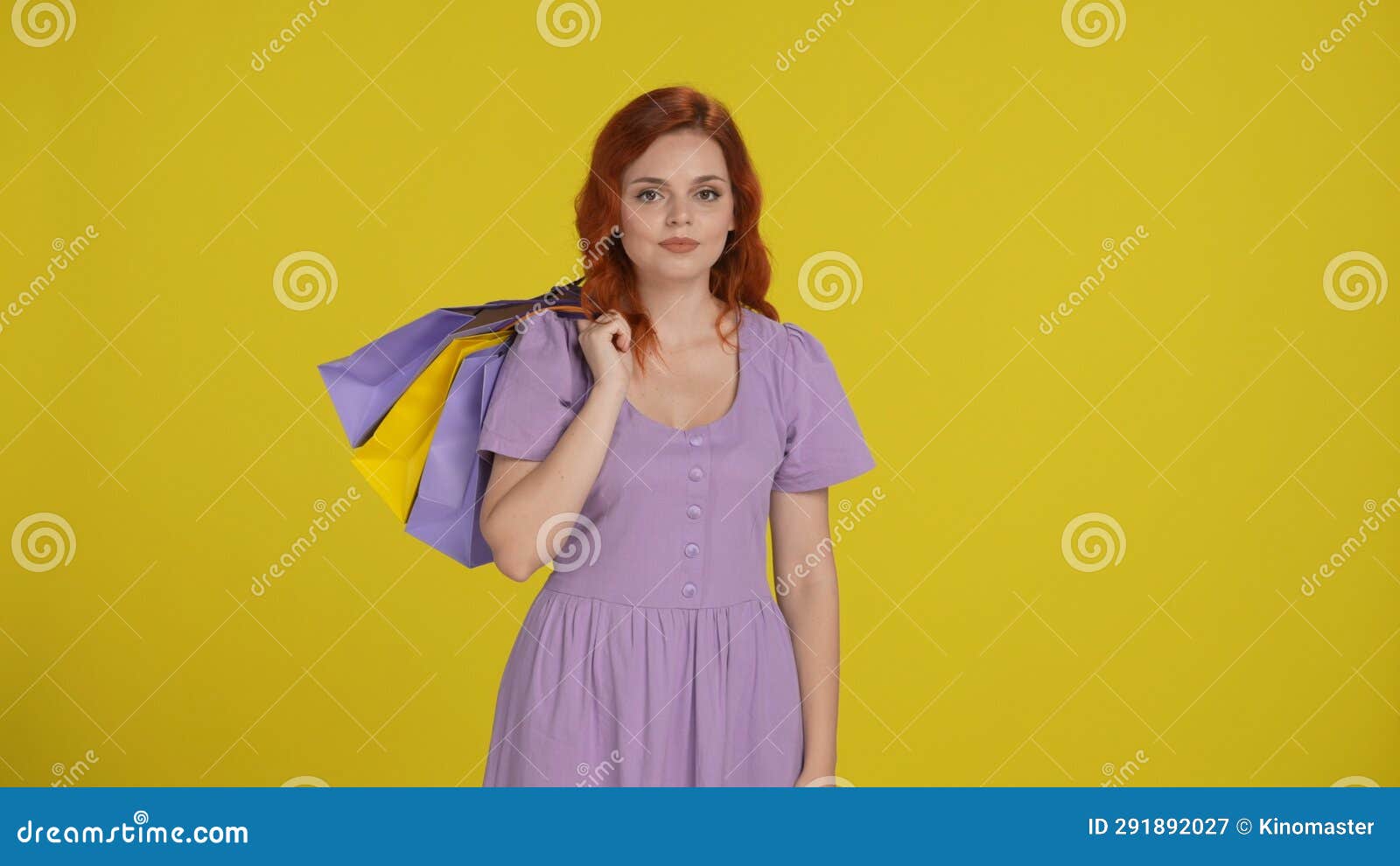 portrait of a woman with shopping bags slung over her shoulder. redhaired woman in the studio on a yellow background.