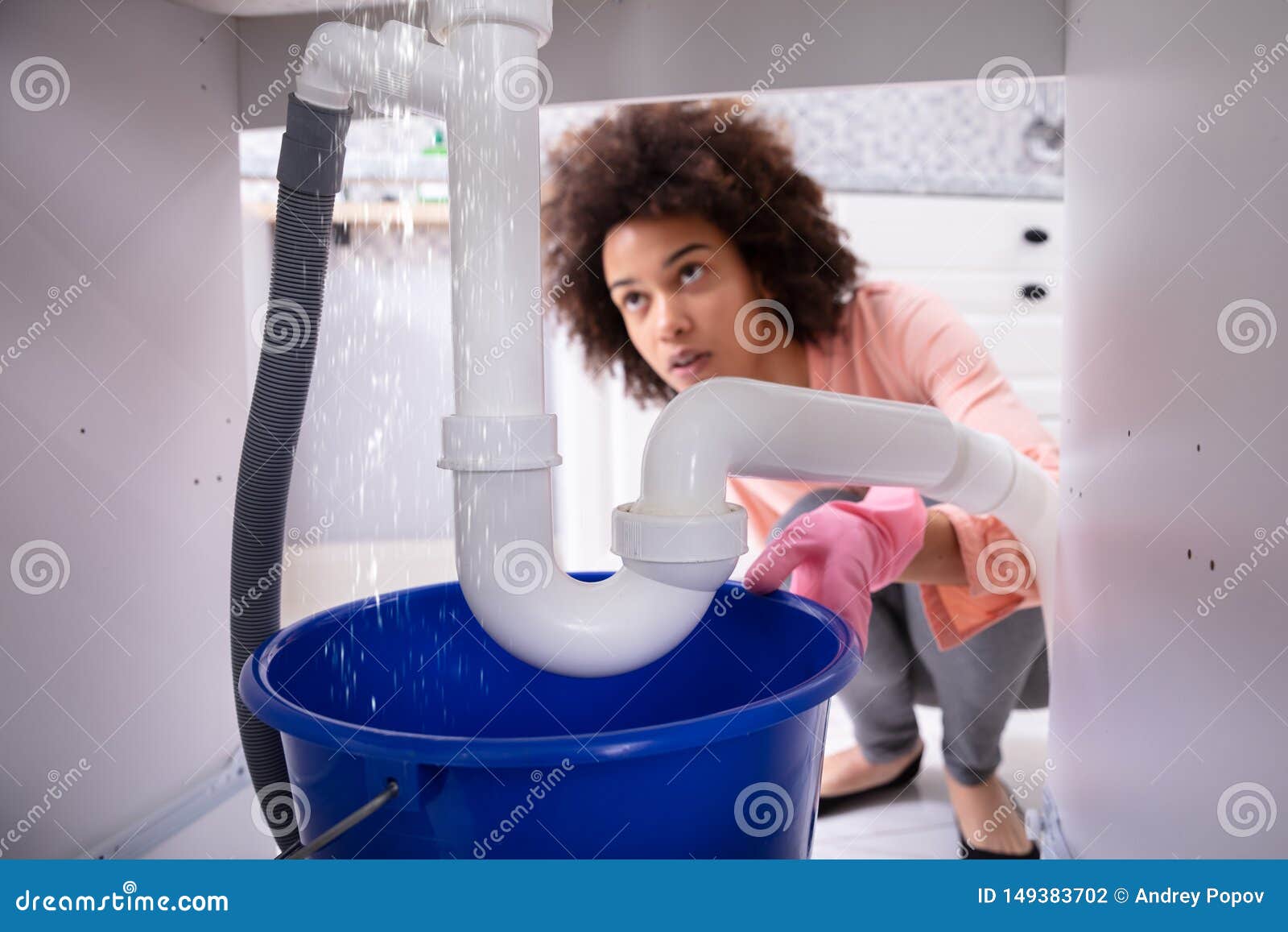 woman looking at water leaking from sink pipe