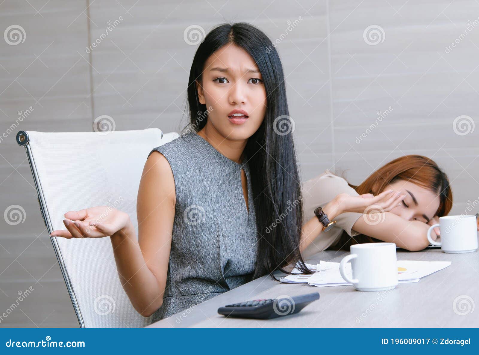 portrait of young asian businesswoman with arms out, shrugging her shoulders,saying: who cares, while workplace during work