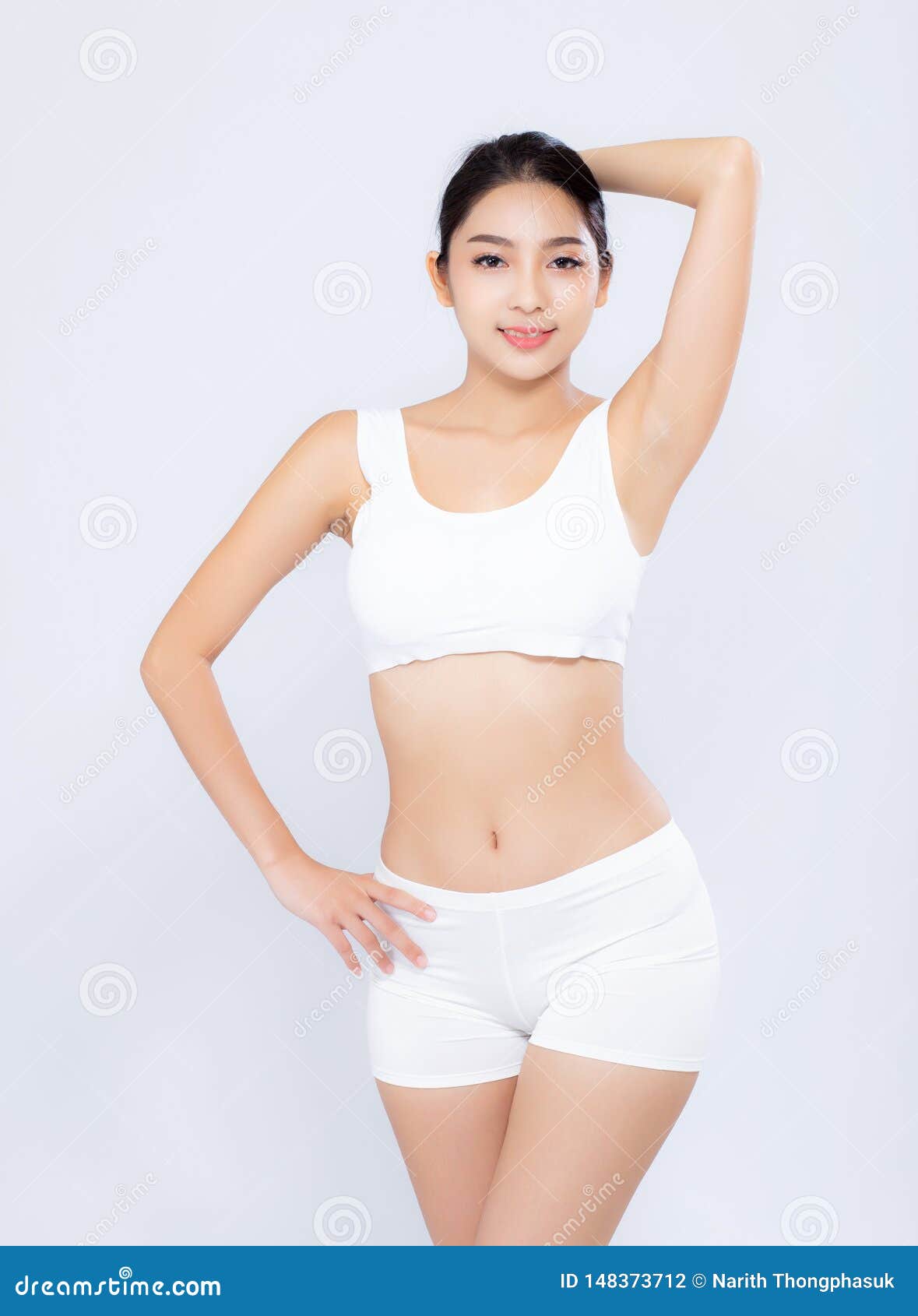 Closeup of fit woman showing her stomach and body in underwear or  sportswear, isolated against blue studio background with copyspace. Toned,  sporty model standing alone. Slim physique and flat tummy Stock Photo