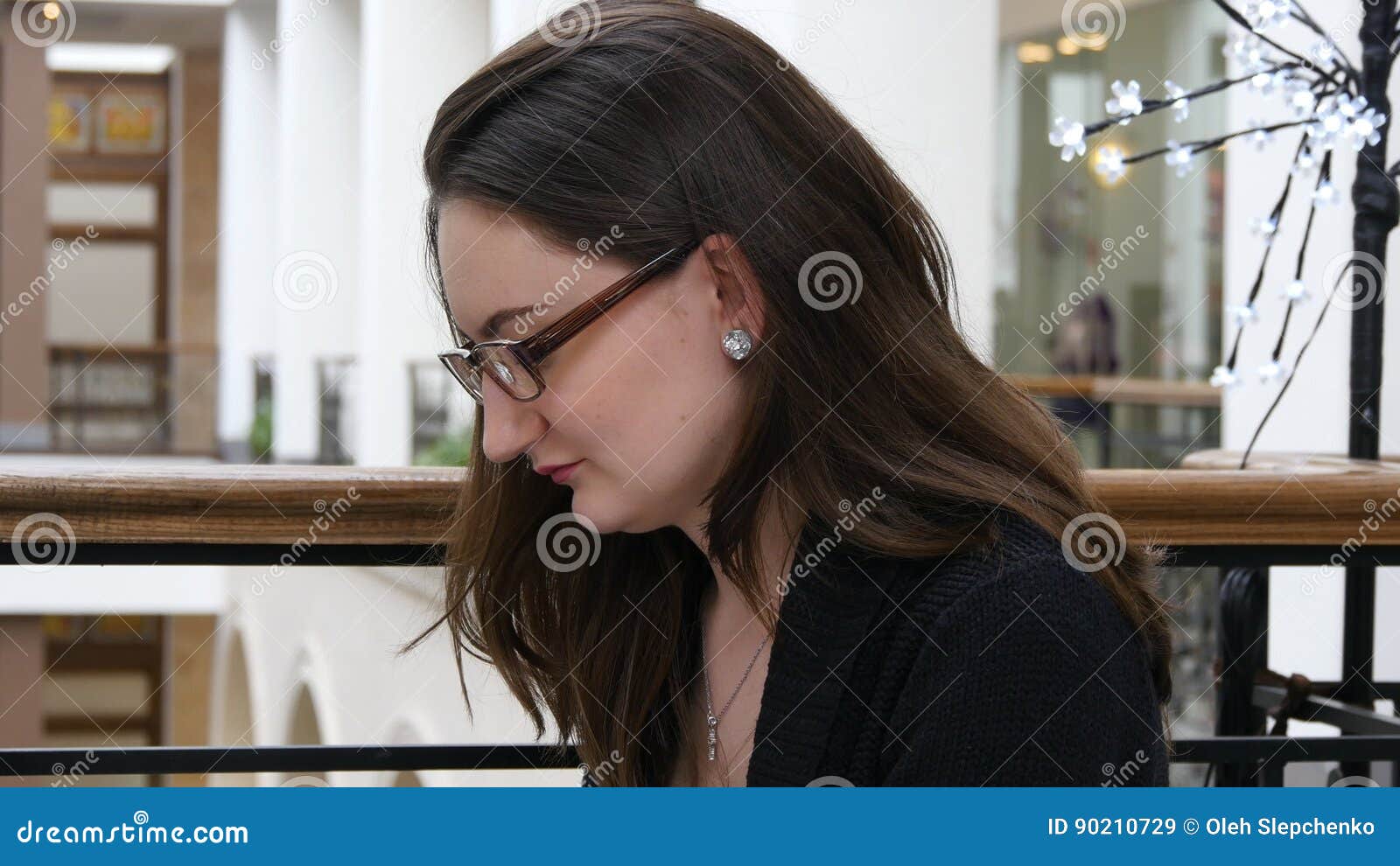 Portrait Of Young Beautiful Girl In Glasses Working In Shopping Mall With Her Laptop She Is 