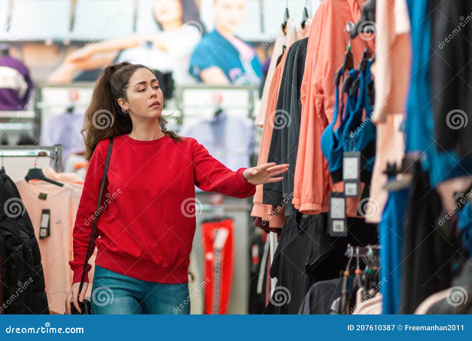 portrait of a young beautiful woman choosing clothes in a store. blurred traiding floor on the background. the concept of shopping