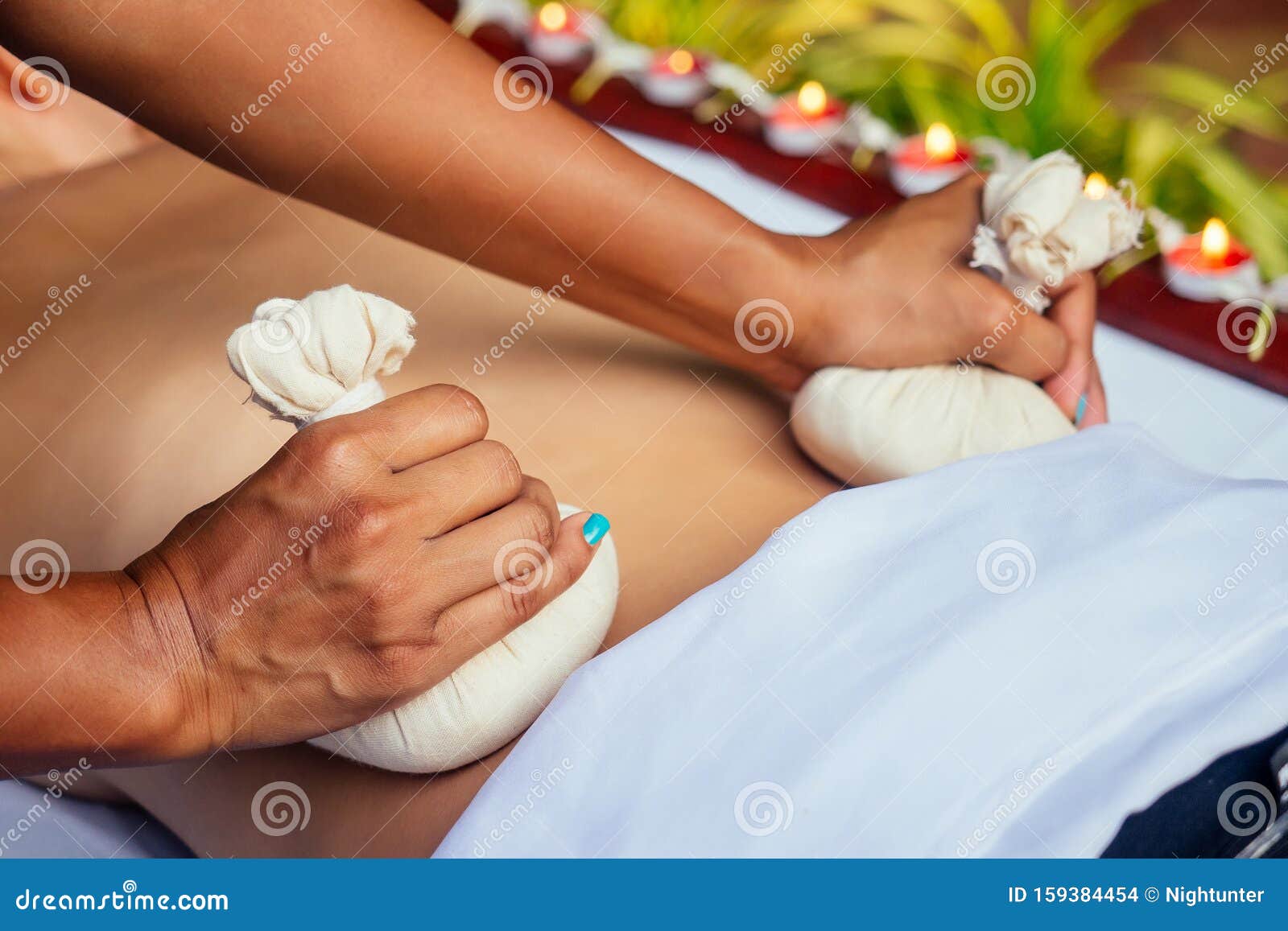 portrait of young beautiful woman lying on a wooden table in spa environment flowers and candles