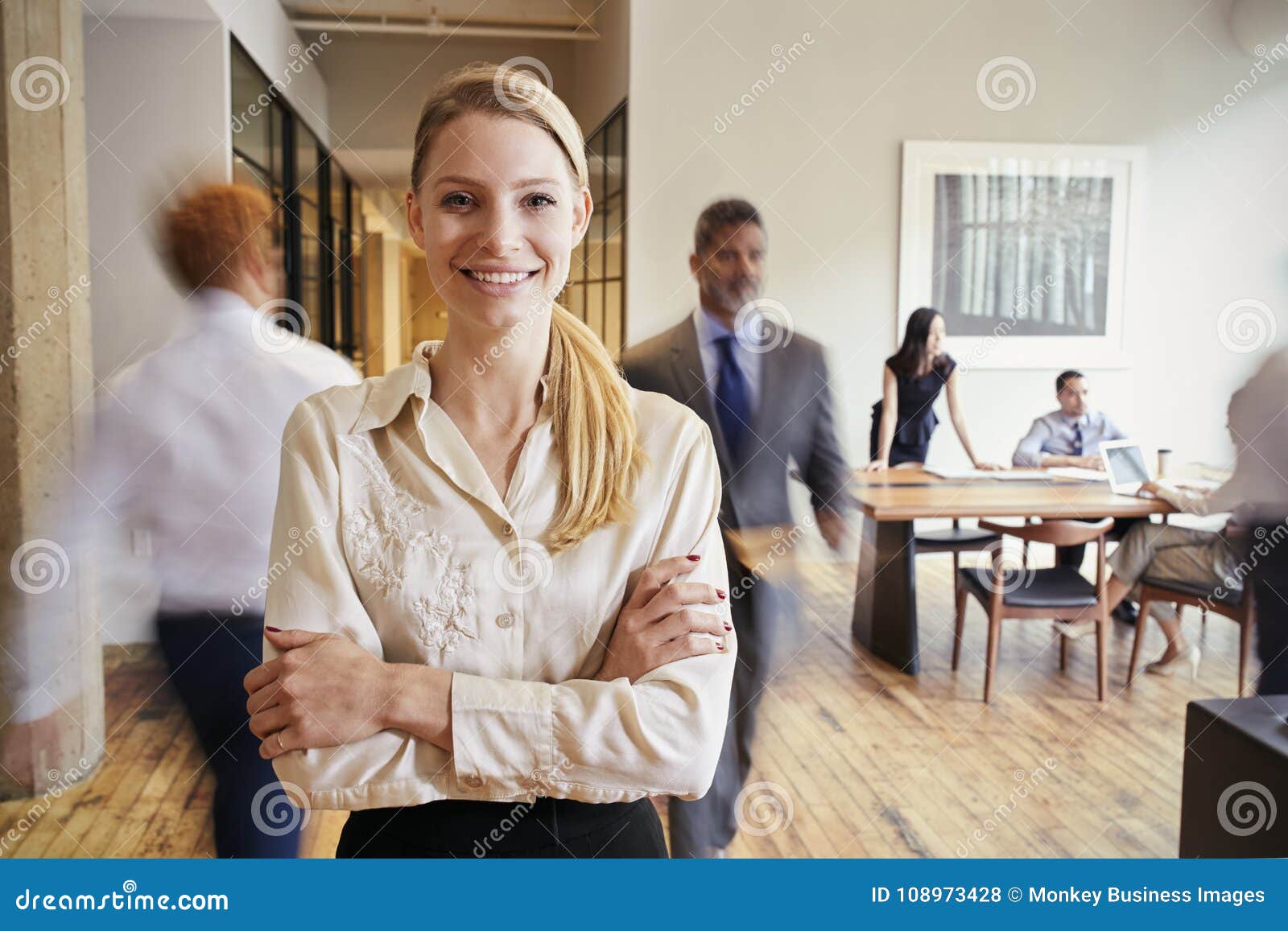 portrait of young blonde woman in a busy modern workplace
