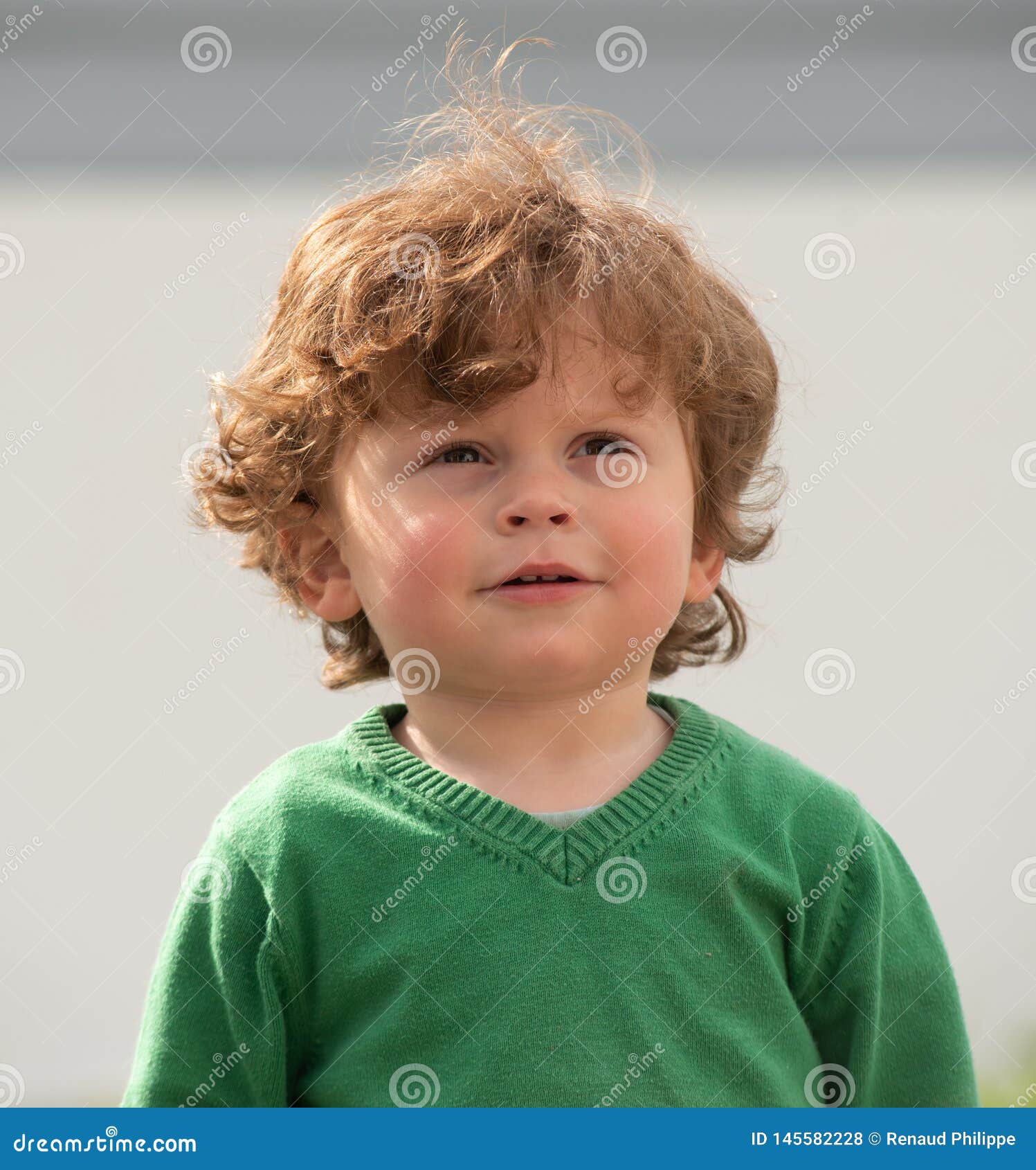 Portrait of Young Boy with Green Sweater Playing Outdoors Stock Photo