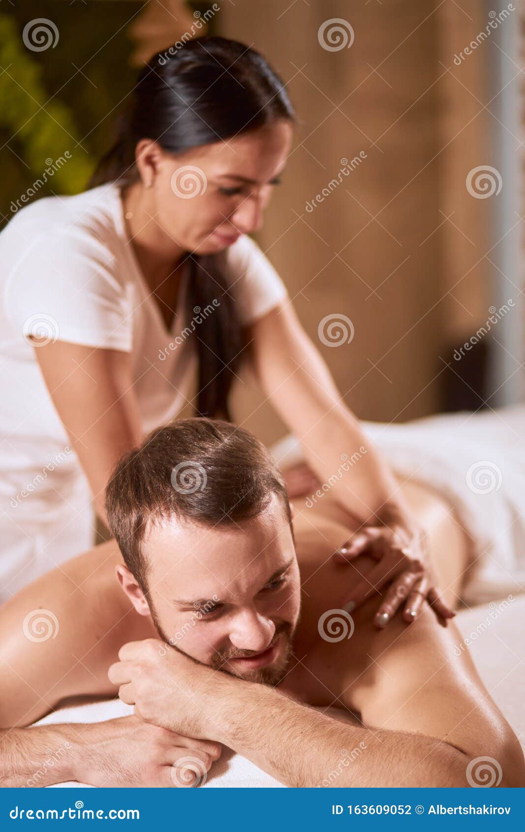 Female hands do a back massage to a man in the salon. Stock Photo by puhimec