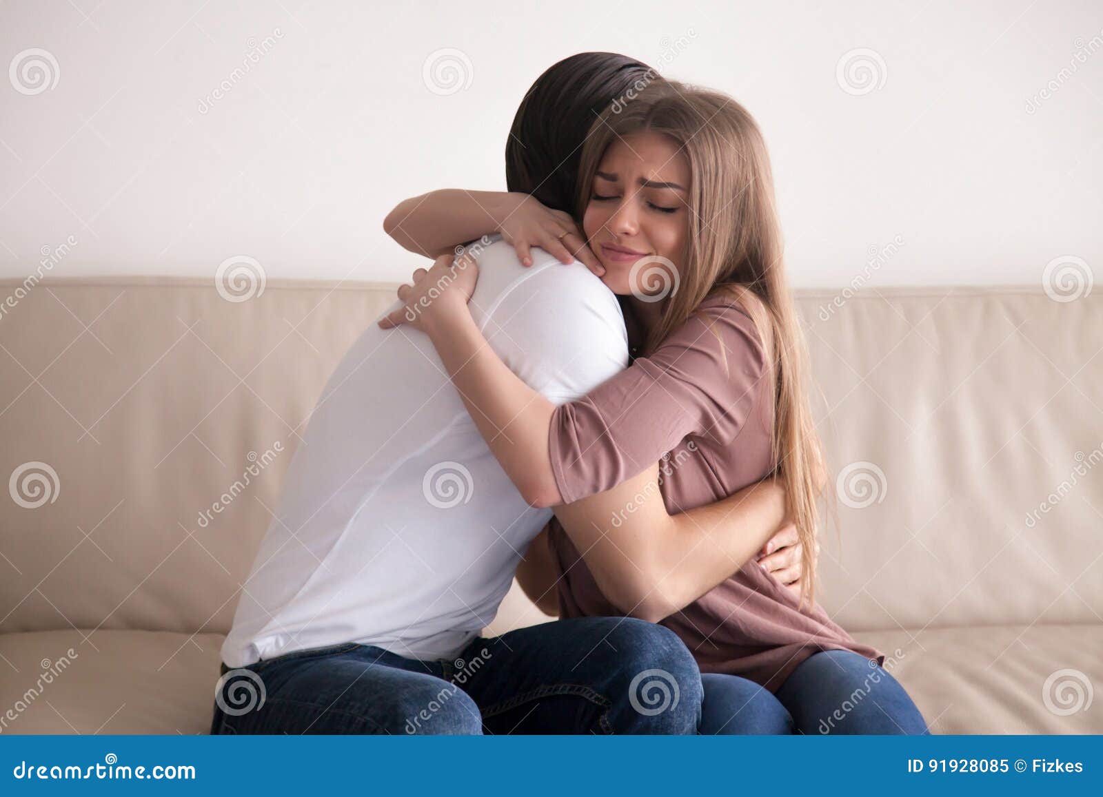 Portrait of Young Couple Hugging Tight Sitting on Couch Indoors ...