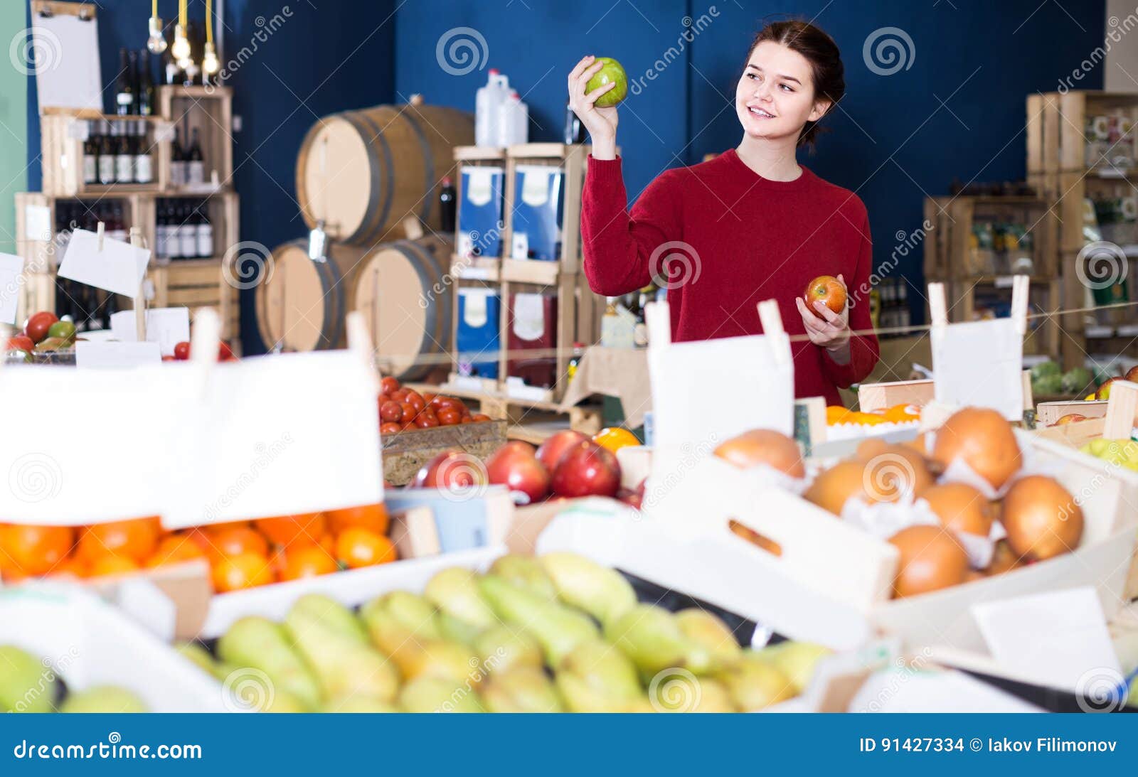 Portrait of Young Customer Selecting Apple in Grocery Stock Photo