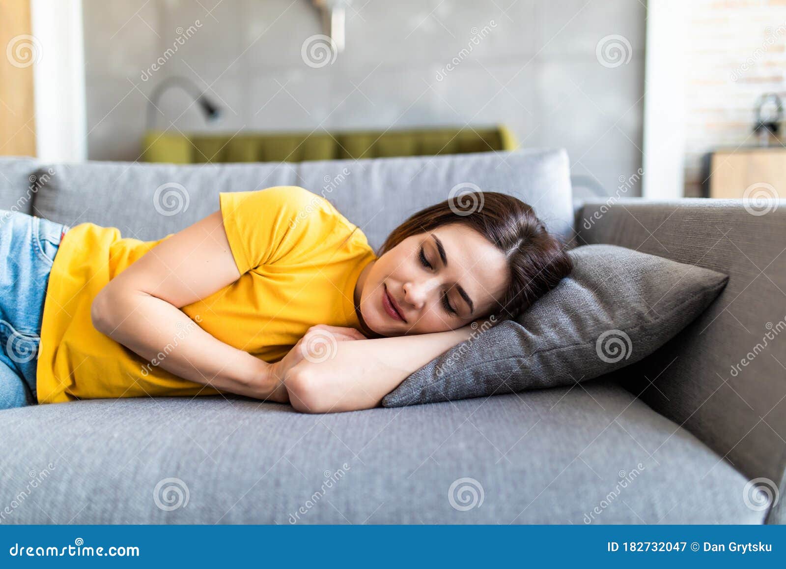 Portrait Of A Young Cute Brunette Girl Sleeping On The Sofa In Light