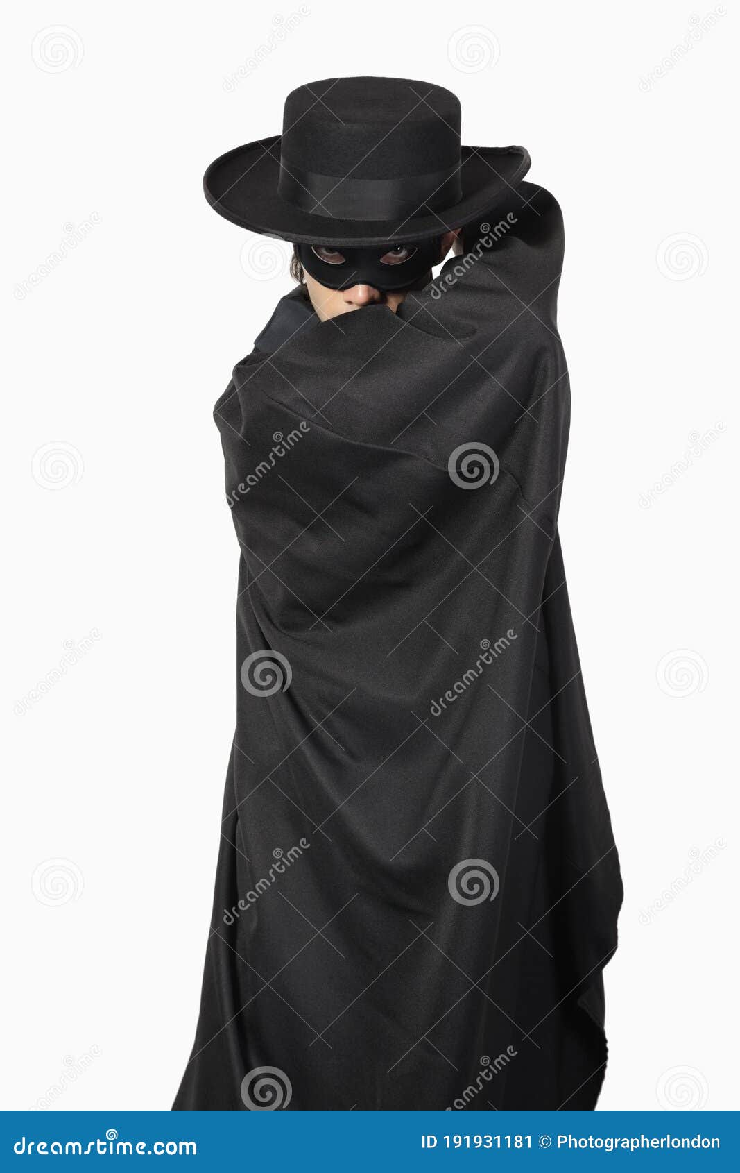 portrait of young man dressed as zorro against gray background