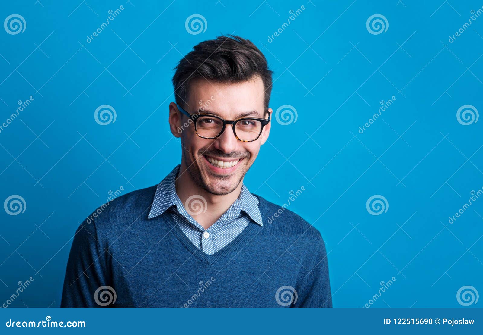 Portrait of a Young Man with Glasses in a Studio on a Blue Background ...