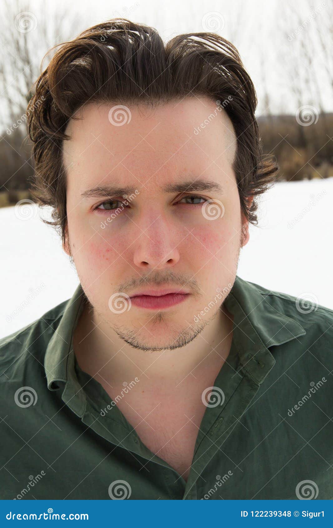 portrait of young man looking at camera and snowy landscape back