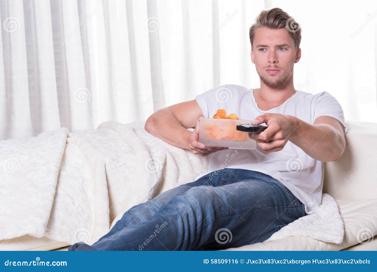 Portrait Young Man  Sitting On Couch  And Eating Chips And 