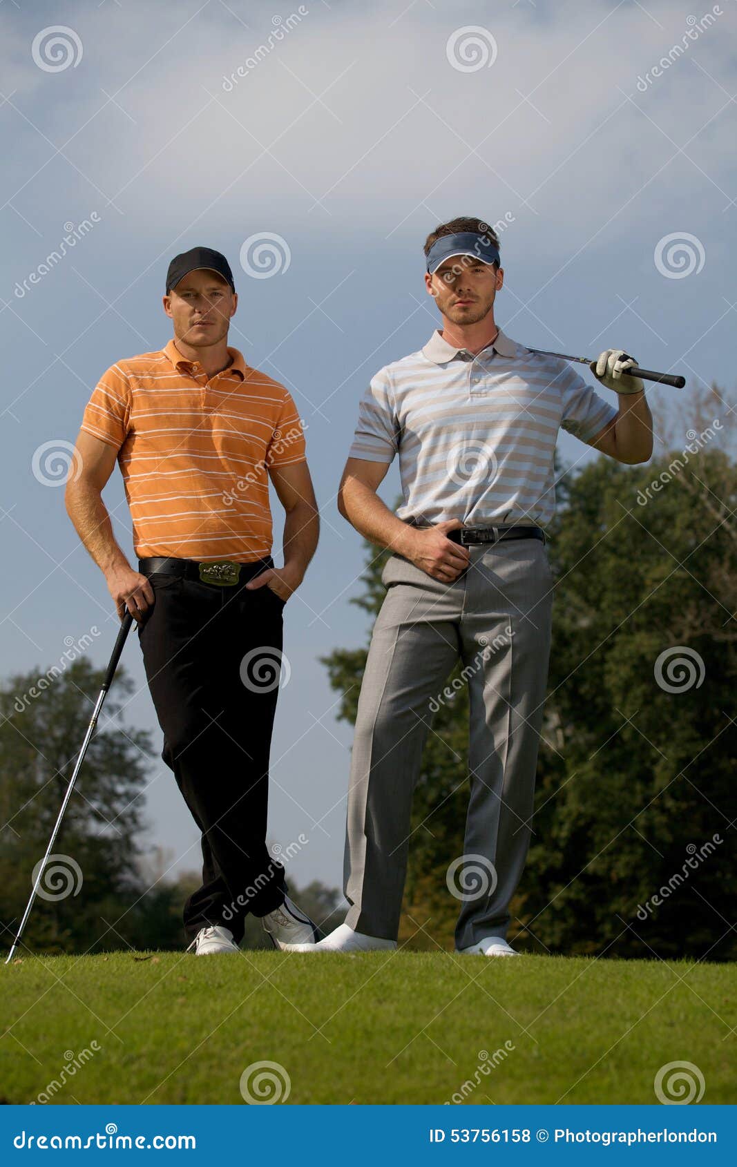 Portrait Of Young Men Standing With Golf Sticks On Golf Course Stock