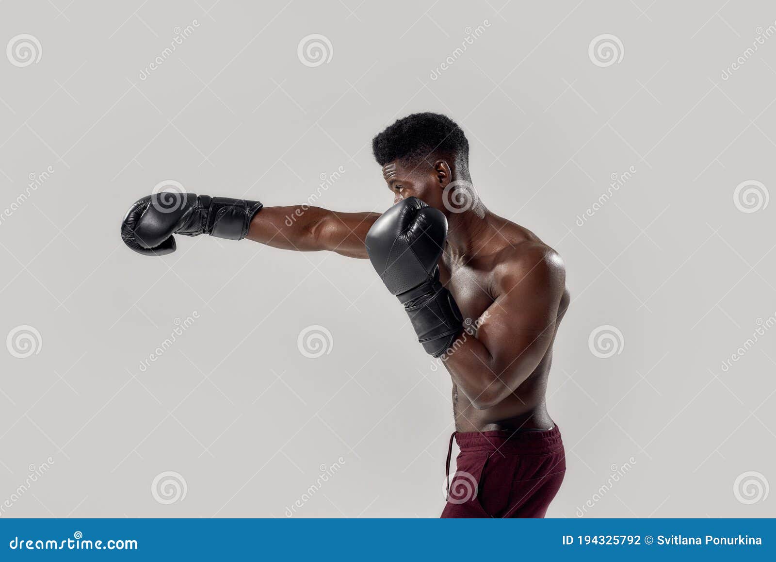 Portrait of Young Muscular African American Male Boxer Looking Aside, Wearing Boxing Gloves, Punching, Standing Isolated Stock Photo picture image