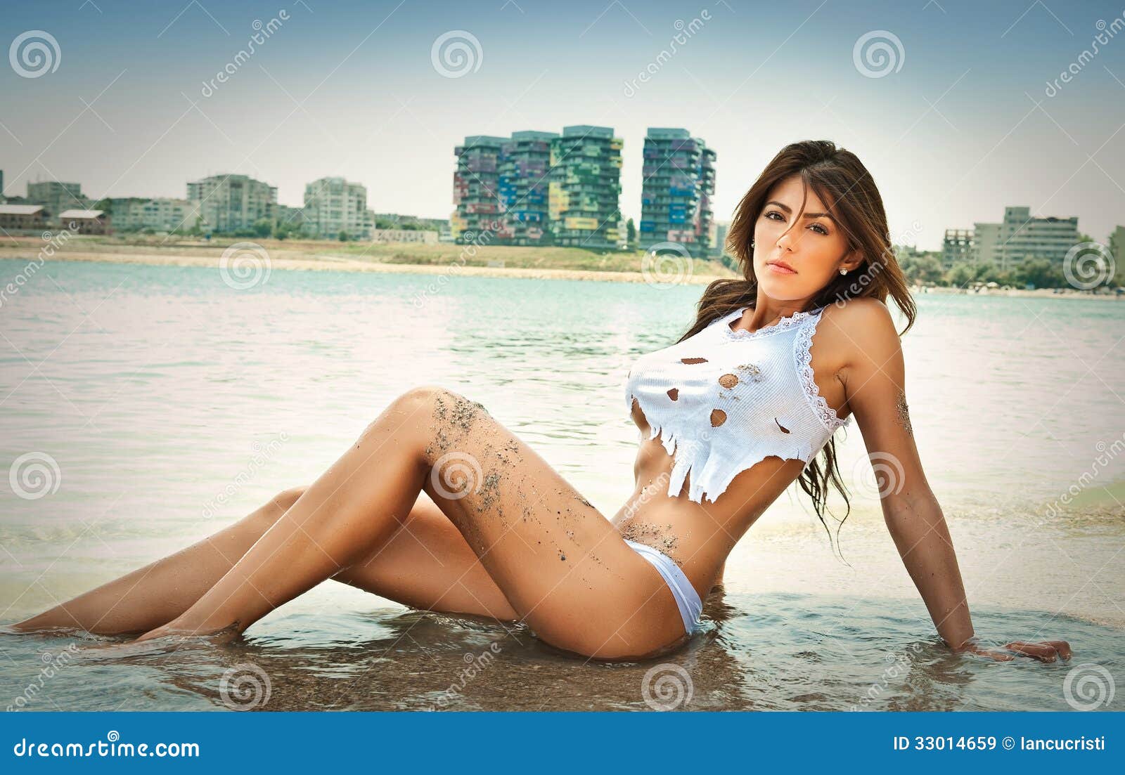 portrait of young brunette girl in white bikini and wet t-shirt at the beach