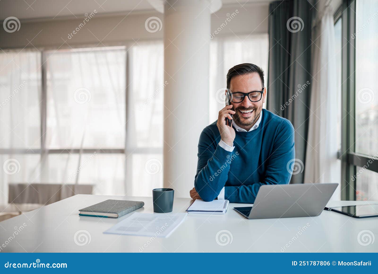 portrait of young smiling cheerful entrepreneur in casual office making phone call while working