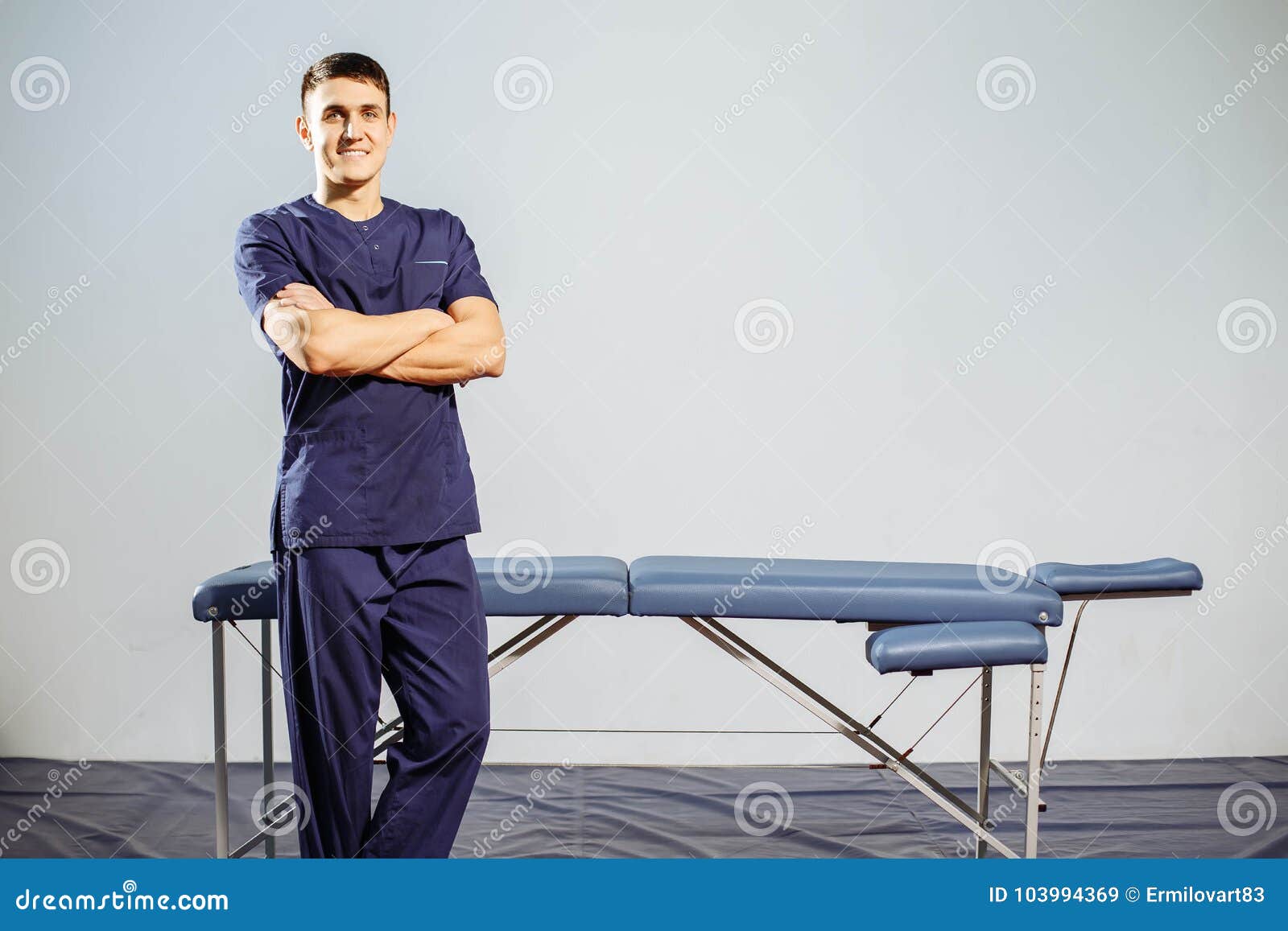 portrait of young smiling man in uniforme near massage couches.