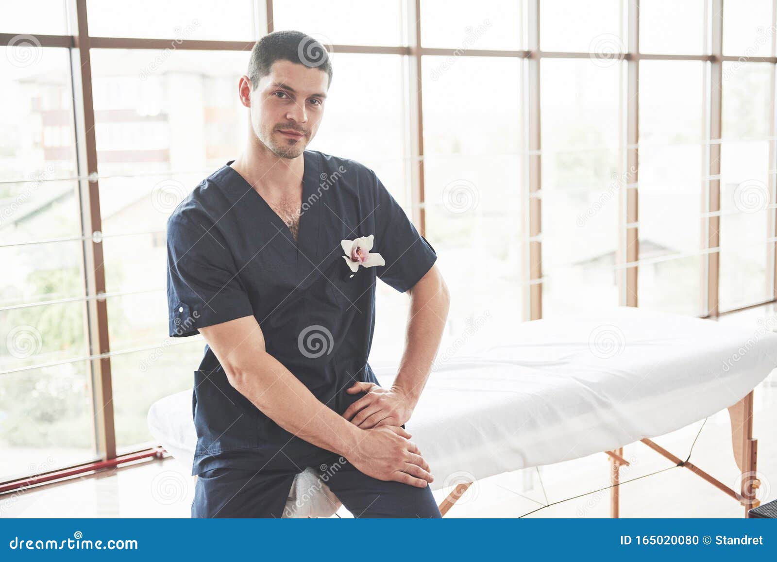 portrait of young smiling man in uniforme near massage couches