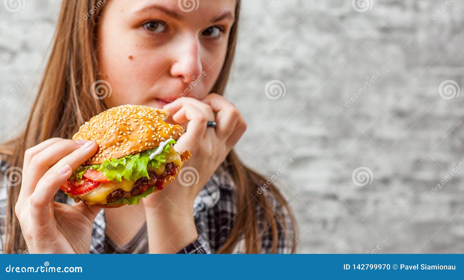 Portrait Of Young Teenager Brunette Girl With Long Hair Eating Burger