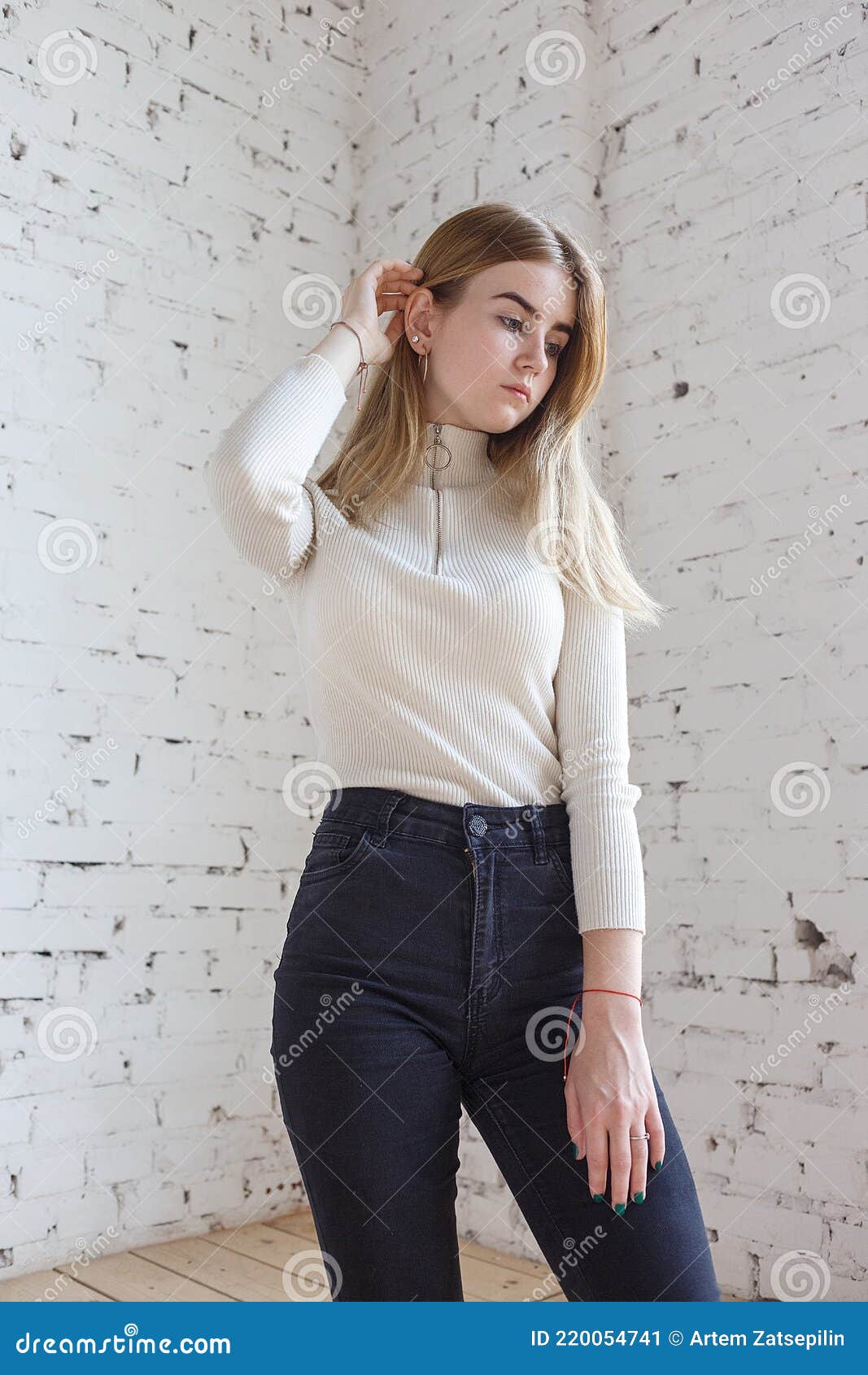 Attractive and pretty girl wearing black jeans and white T-shirt. Beautiful  young woman looking away while sitting with crossed legs on chair against  white background. Black and white. Stock Photo | Adobe