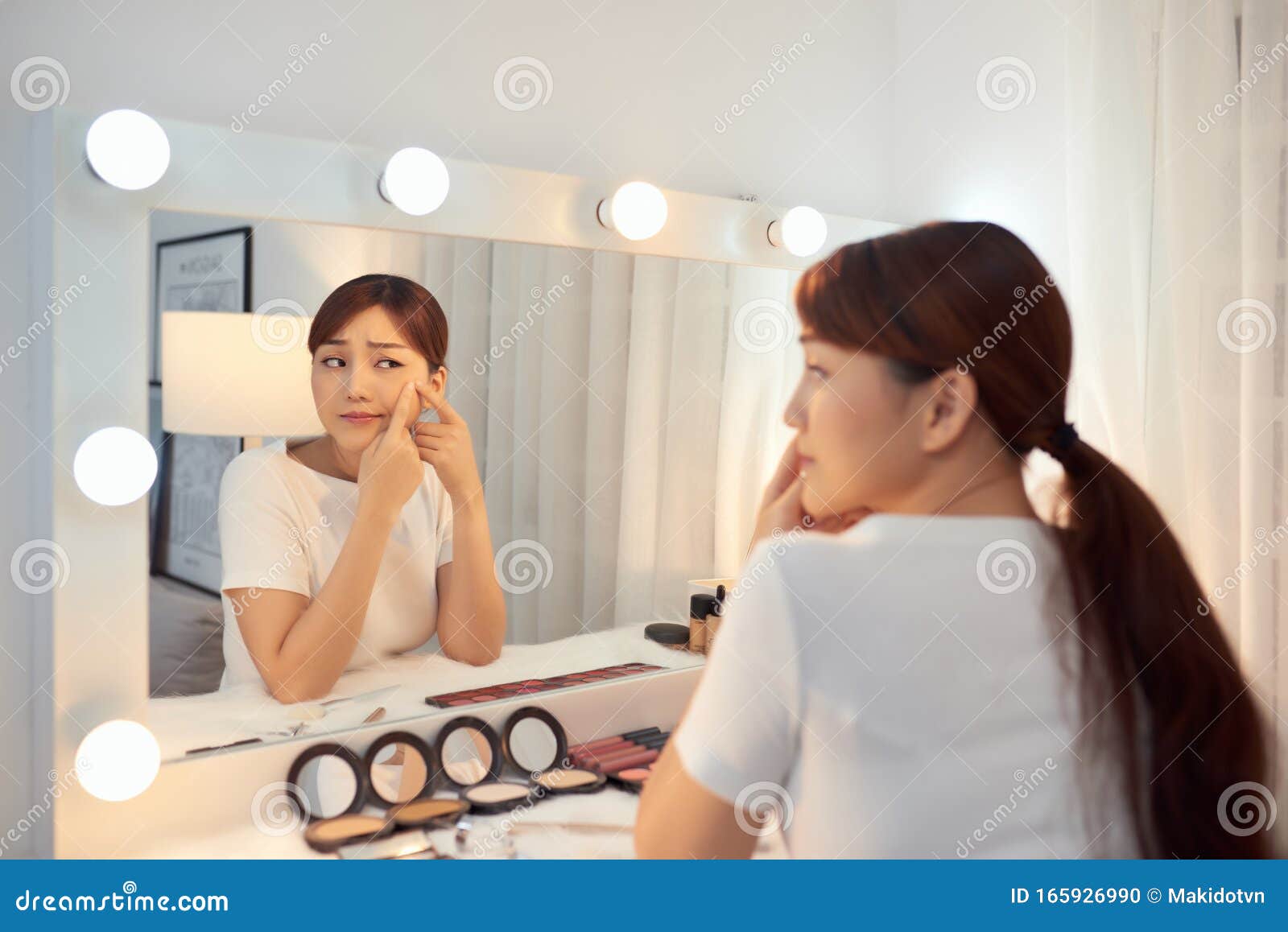 Portrait of Young Woman with Acne Problem Looking in Mirror Stock Photo