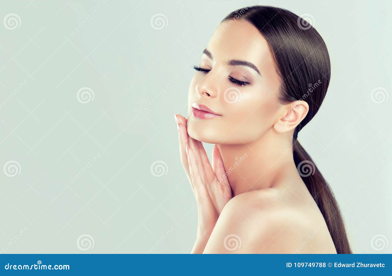 portrait of young woman with clean fresh skin and soft, delicate make up. woman is touching to own face tenderly.