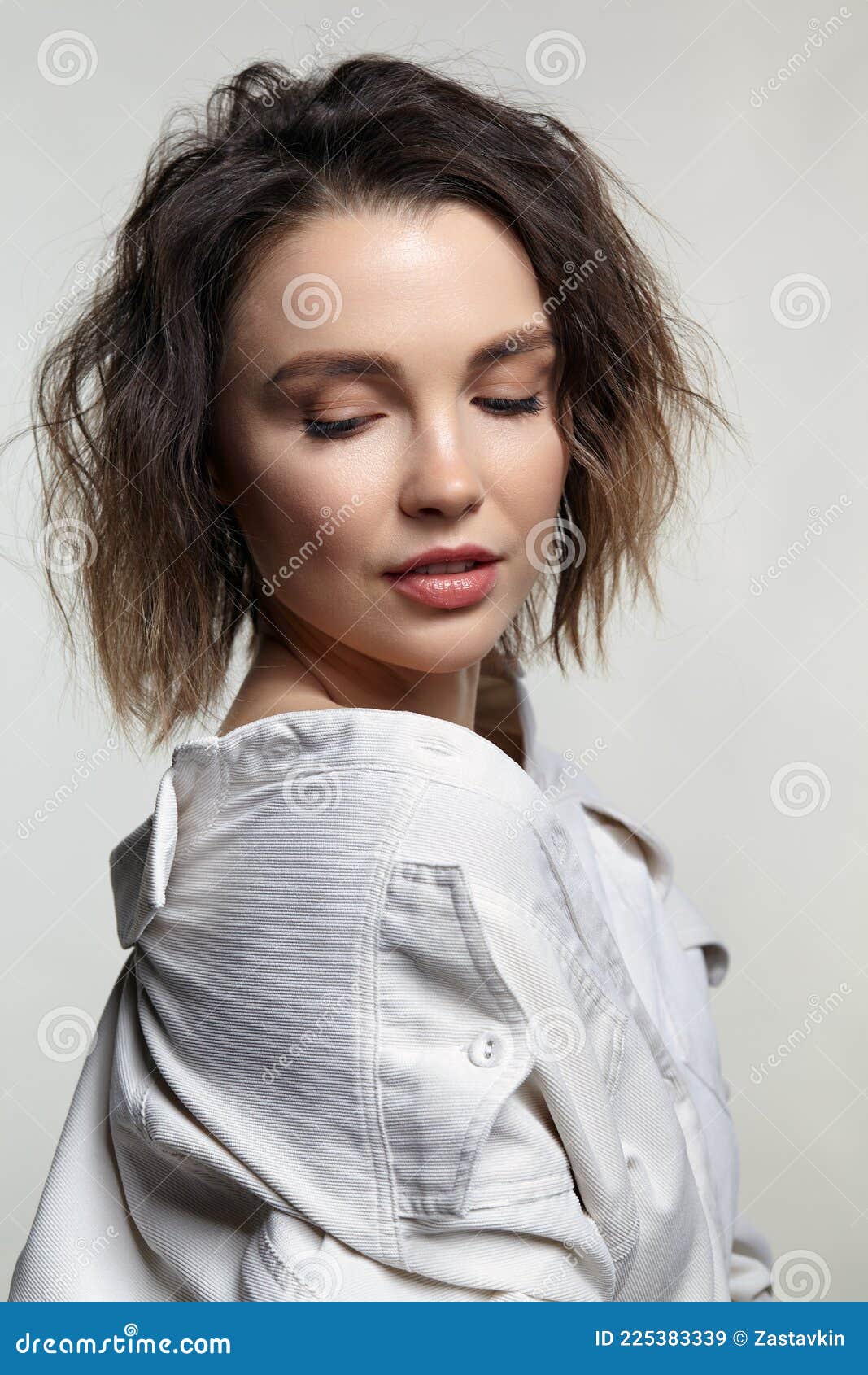 portrait of young woman with downcast eyes. female posing in milky white corduroy shirt