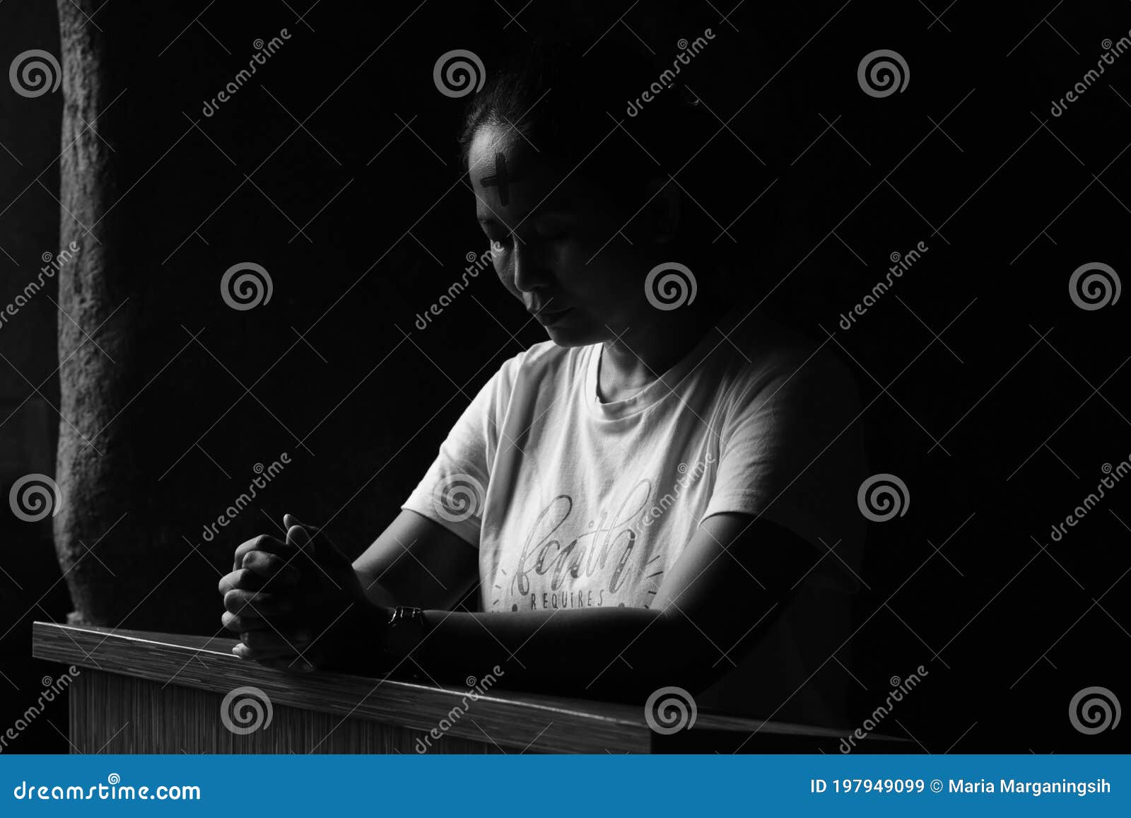 portrait of young woman kneeling and praying in silent prayer pose, on black and white background. ash wednesday concept.