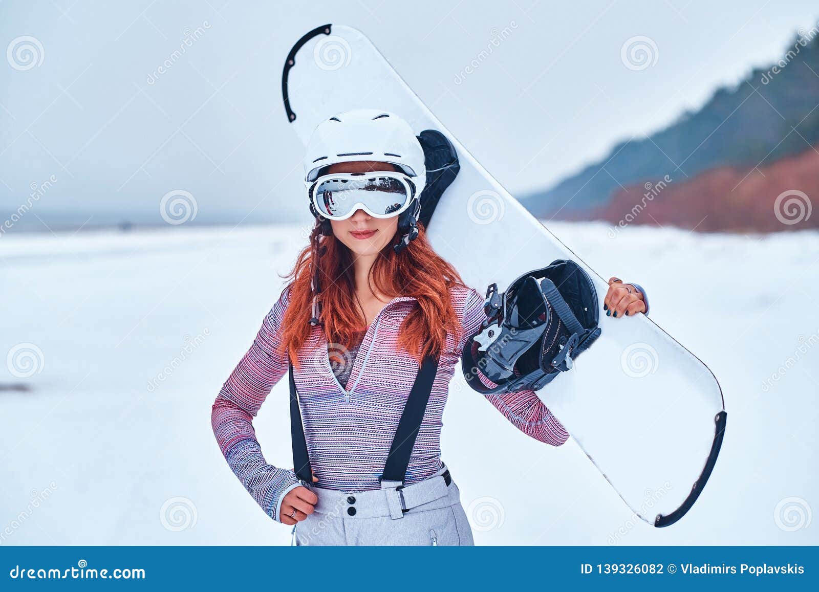 Portret Die Van Een Roodharigemeisje in Beschermende En Brillen Een Snowboard Houden, Op Een Sneeuwstrand Stock Foto - Image of zeker: 139326082