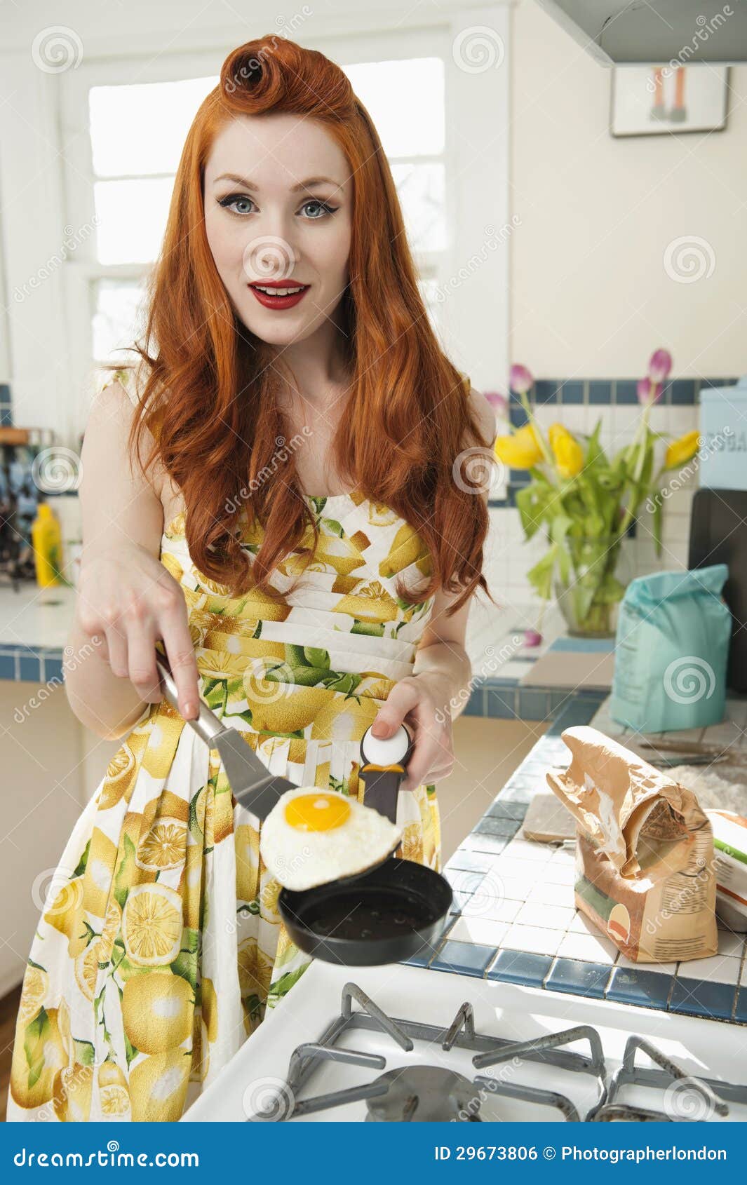 Portret młodej redheaded kobiety kulinarny omlet. Portret młode redheaded kobiety gotuje omlet