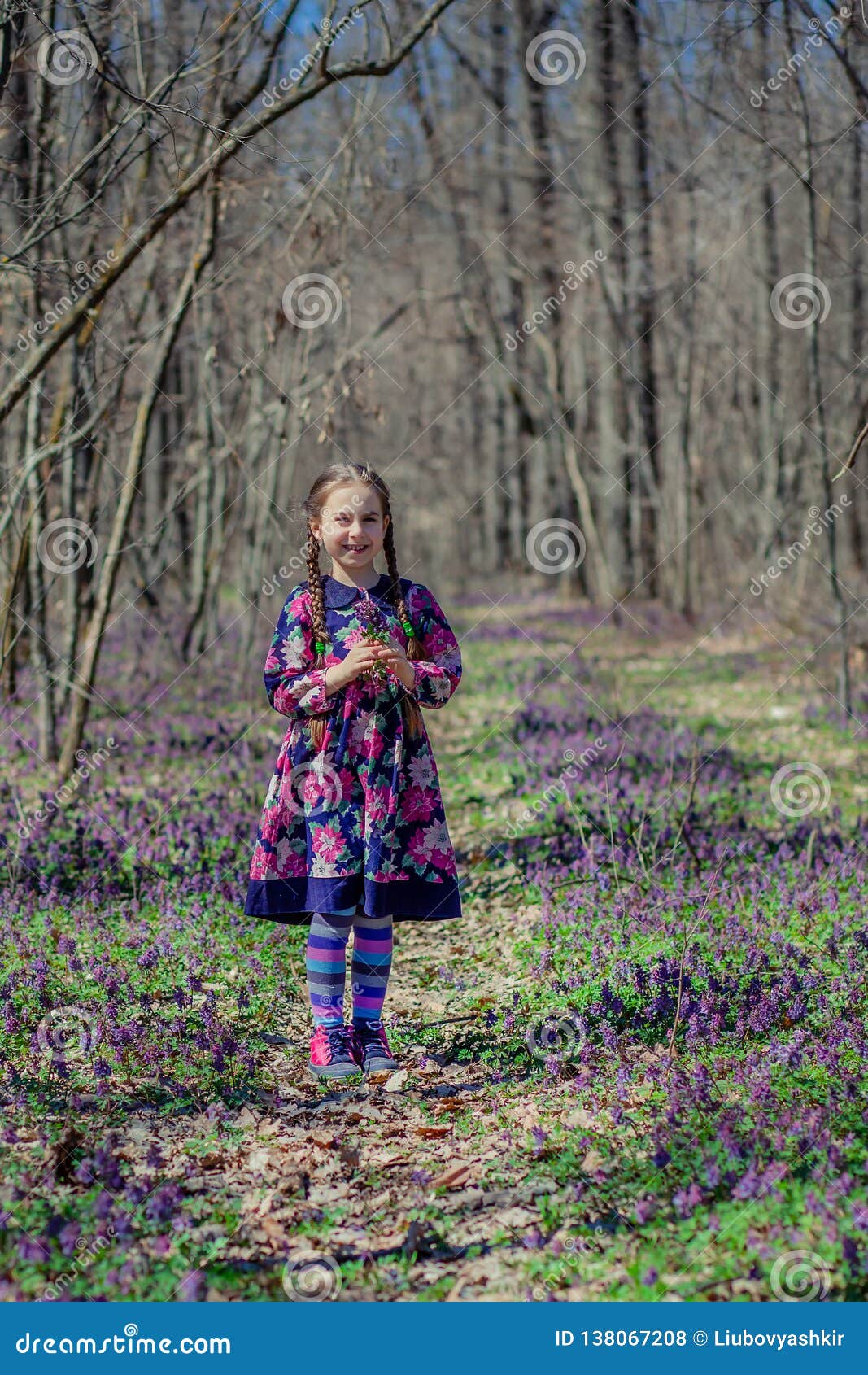 Portret piękna mała dziewczynka z corydalis kwitnie Chodzić w wiosna lesie na słonecznym dniu