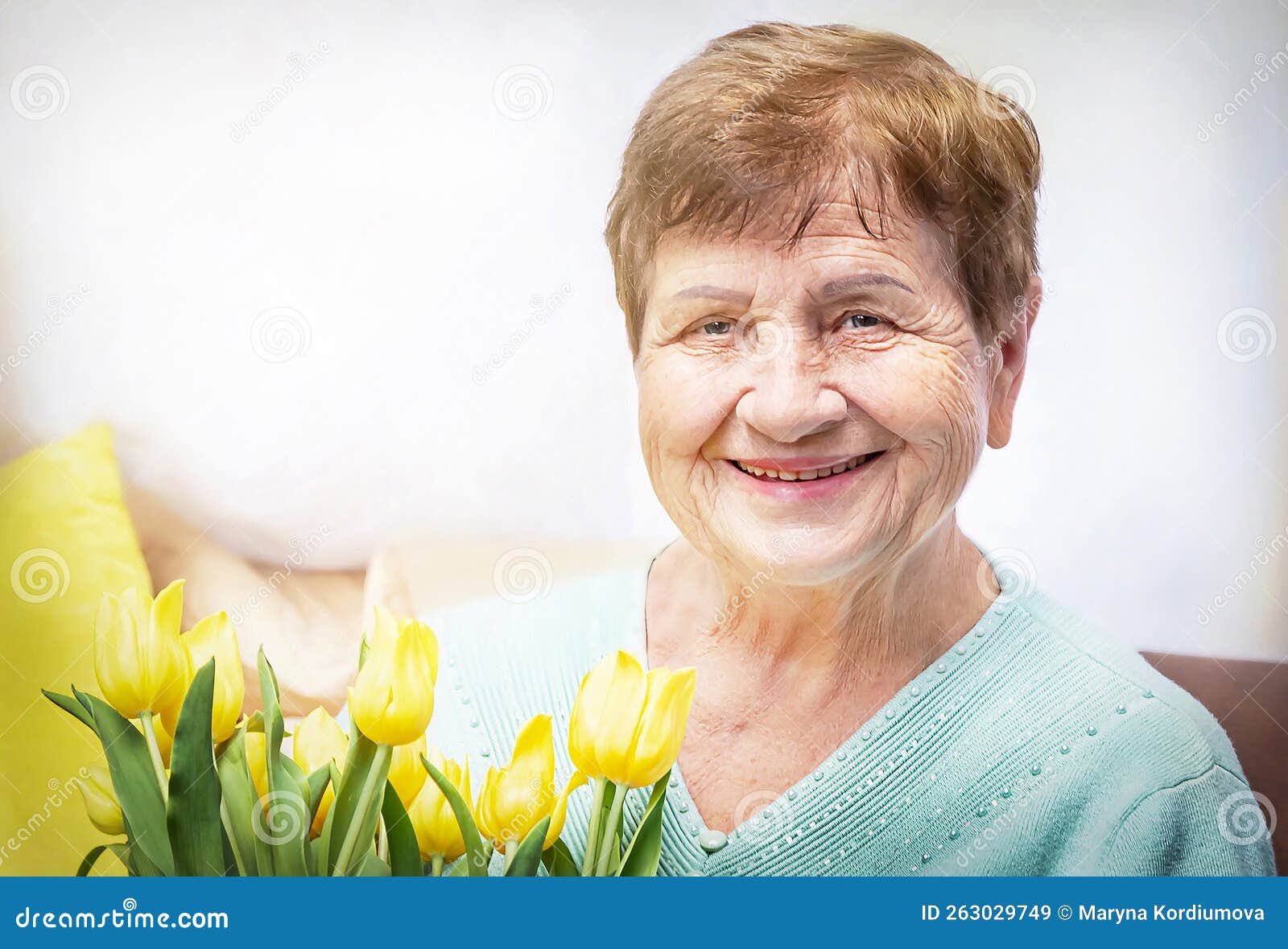 portret of smiling, positive senior elderly woman with bunch of yellow flowers tulipan. happy, healthy grandmother.