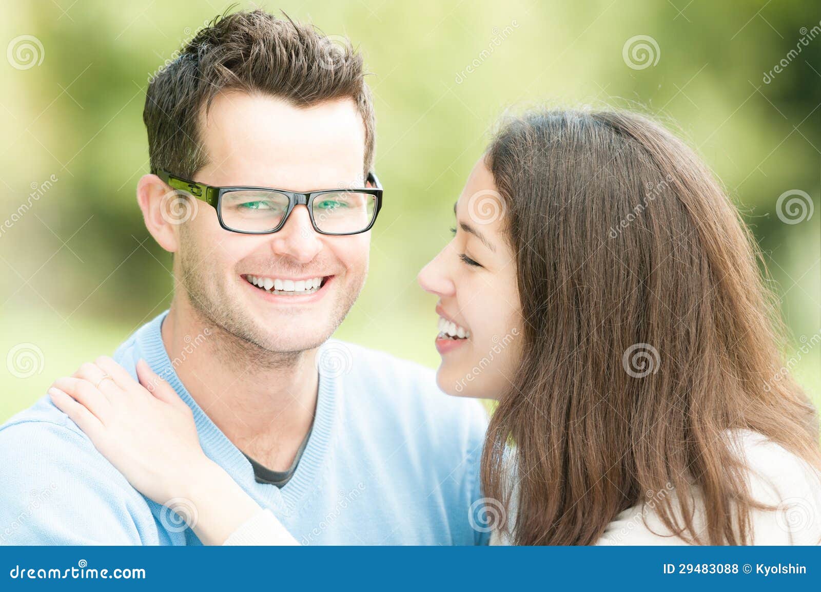 Portret van de gelukkige jonge mens en vrouw in park. Portret van mooi romantisch paar. Mensen die in park dateren. Mooie vrouwen met mannen in glazen en blauwe trui. Groene aard als achtergrond. Jonge positieve familie die vrije tijd hebben buiten.