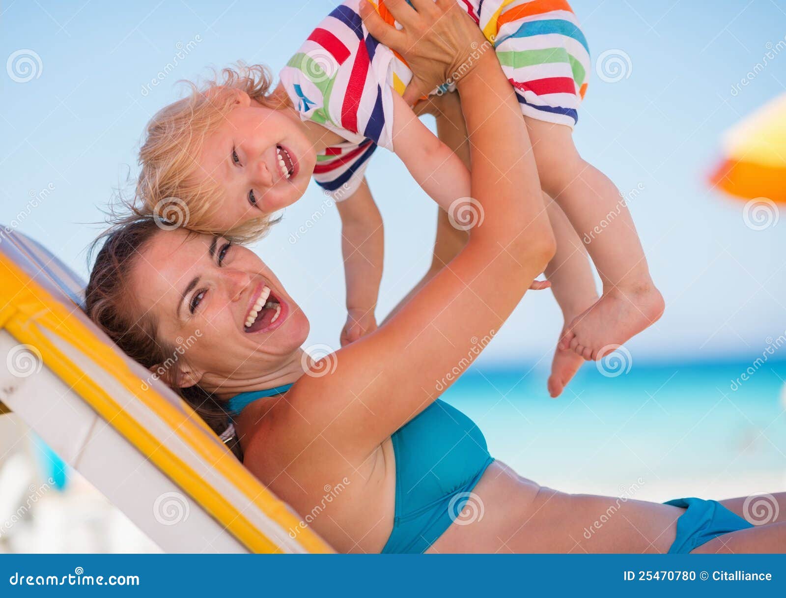 Portret van moeder het spelen met baby op strand. Portret van het gelukkige jonge moeder spelen met babymeisje op strand