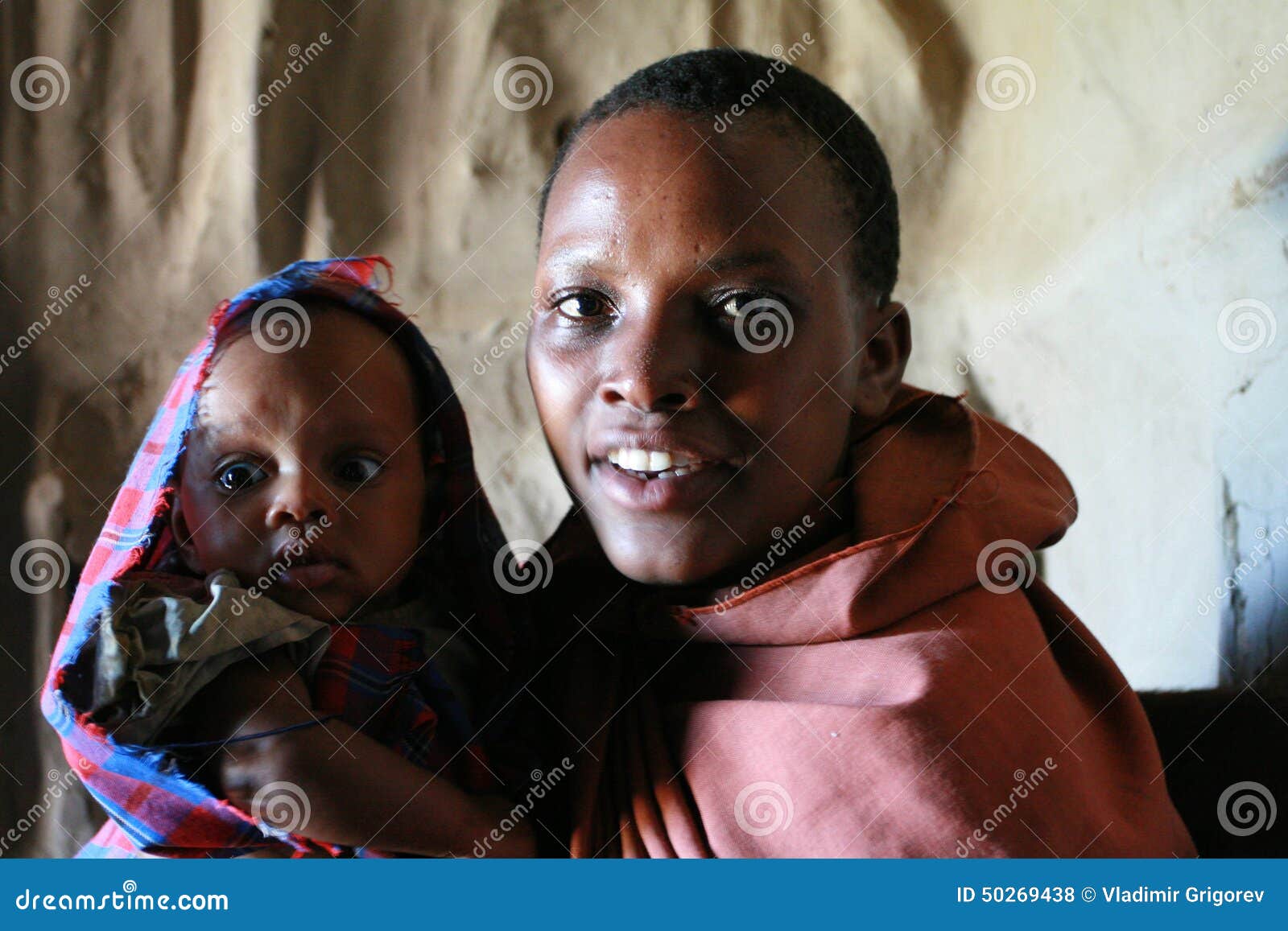 Portret van zwarte met baby binnen huttenstam Maasai. Het Park van de Meseranislang, Arusha, Tanzania - Februari 14, 2008: Het binnenland van het huis Maasai, Zwarte in gedrapeerde robe, houdt een baby, close-upportret